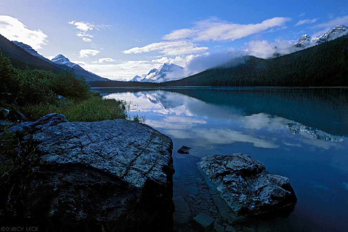 The Waputik Range in the Canadian Rockies reflect in the calm waters of Upper Waterfowl Lake at sunrise, Canada