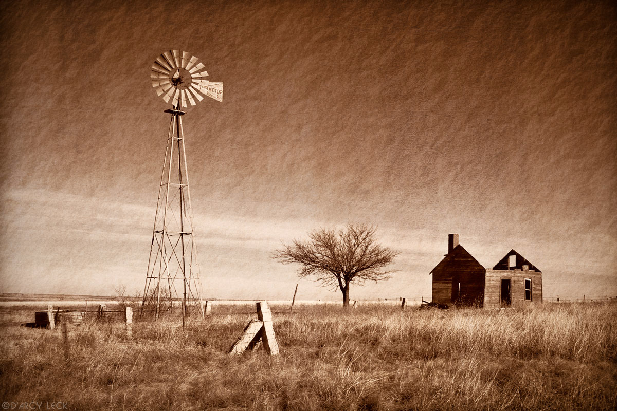 Windmill and old roofless run down homestead near Russell, Kansas