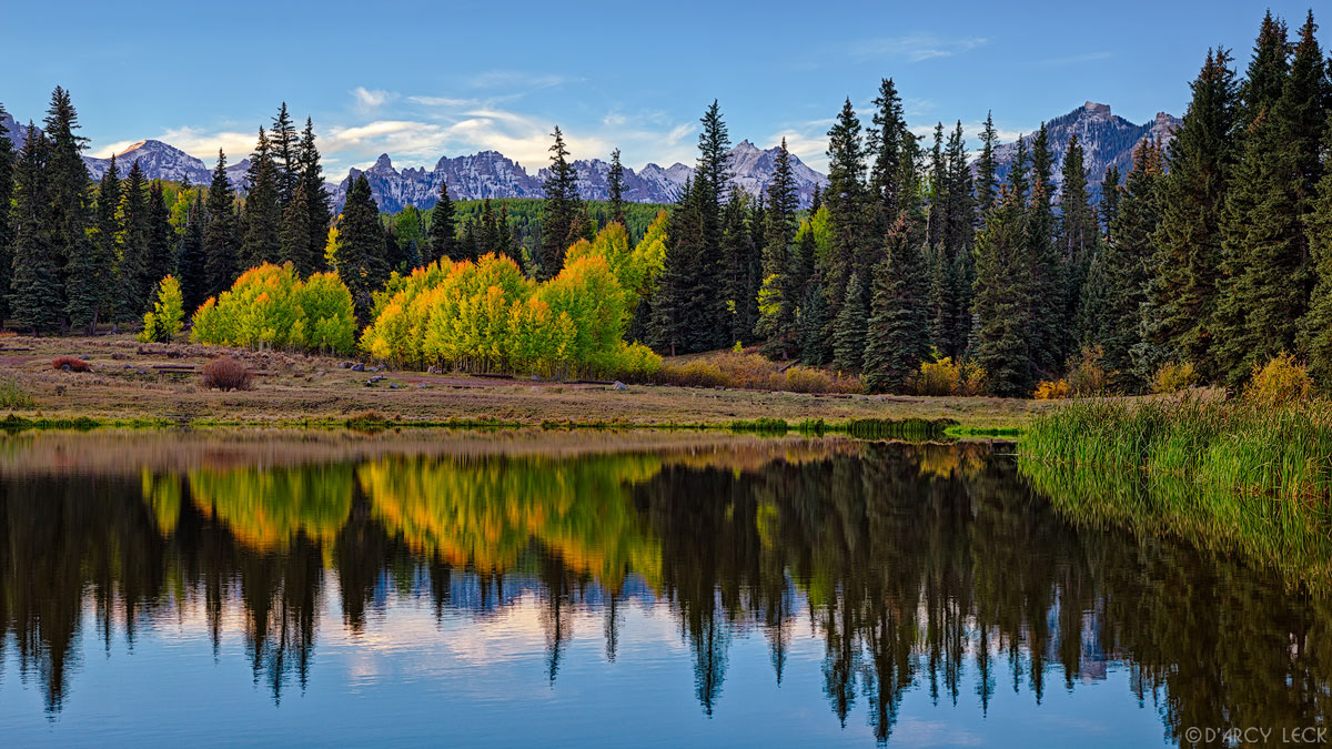 San Juan Mountains and forest in early Autumn colors reflect in Beaver Lake at dawn, Colorado