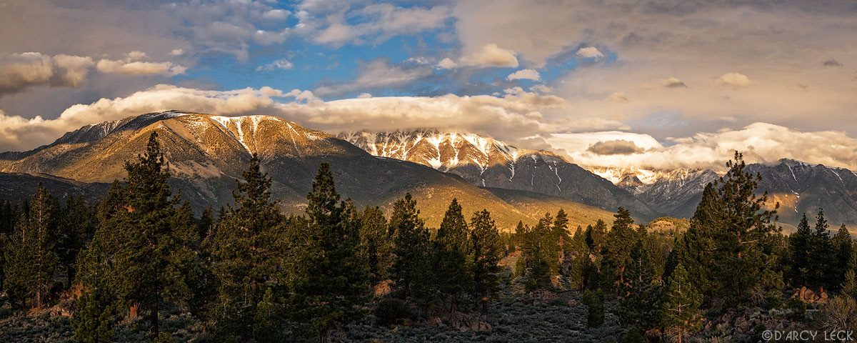 Clearing storm clouds enshroud tops of peaks of Sierra Nevada Mountains in John Muir Wilderness at sunrise, California