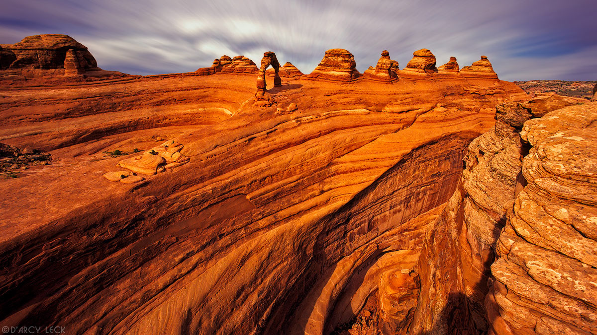 Delicate Arch stands on cliff with other sandstone formations in Arches National Park, Utah
