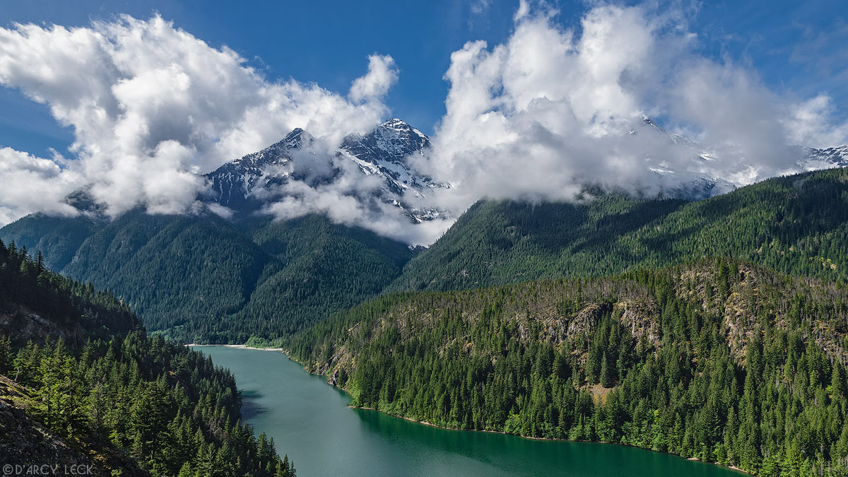 Cloud enshrouded Colonial Peak rises up from Diablo Lake, Washington