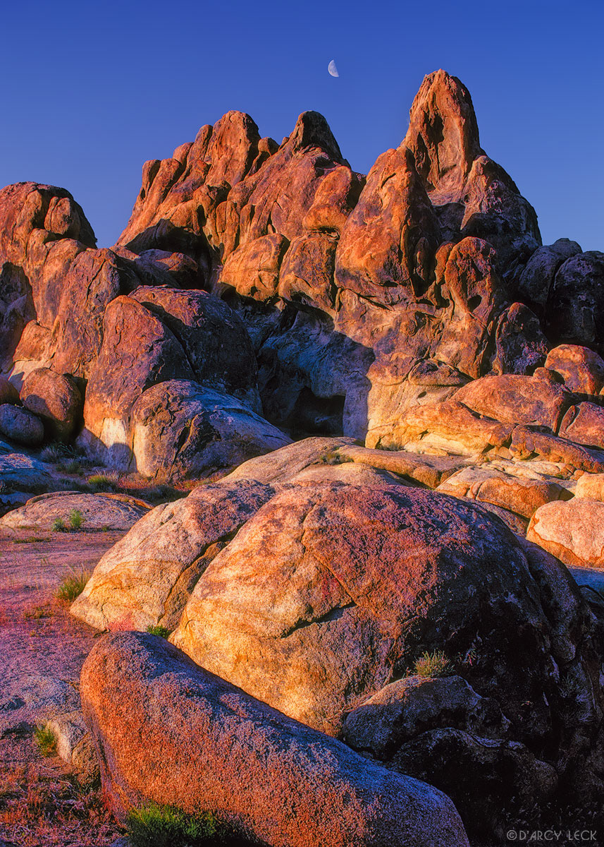 Half moon over rock formations in Alabama Hills, California