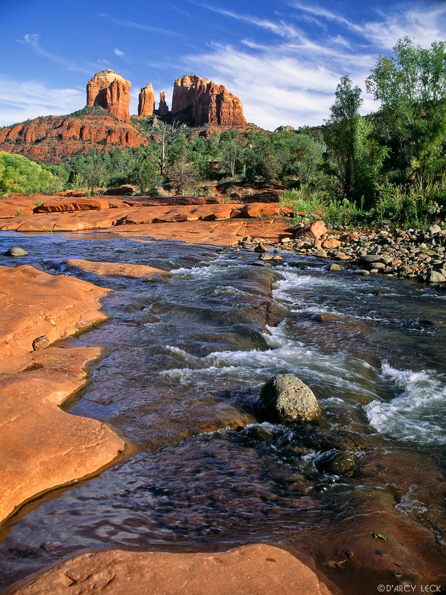 Oak Creek flows through and over red rocks with the Cathedral Rocks in the distance, Arizona
