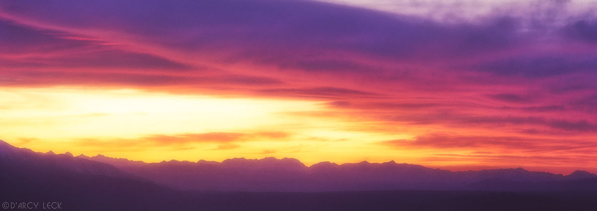Clouds glow orange and red at dusk over the Sierra Nevada Mountains, California