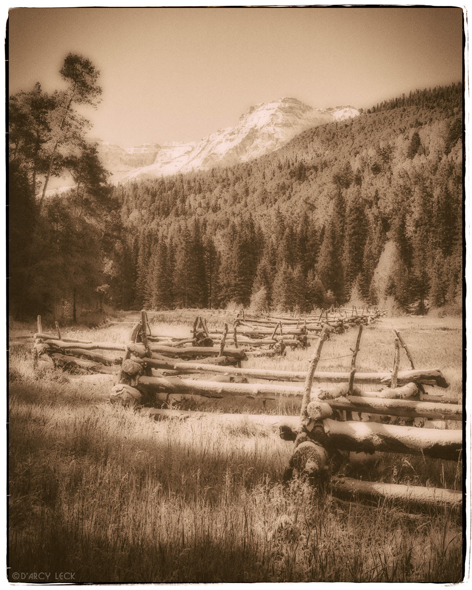 Early Autumn snow on rail fence along field with snow-capped peaks of the San Juan Mountains beyond, Colorado