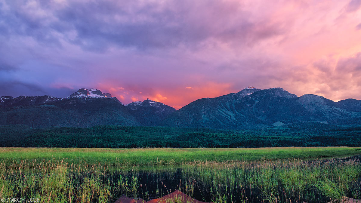 Sunset lights up clouds over Hunters Range of the Monashee Mountains beyond Columbia River, British Columbia, Canada