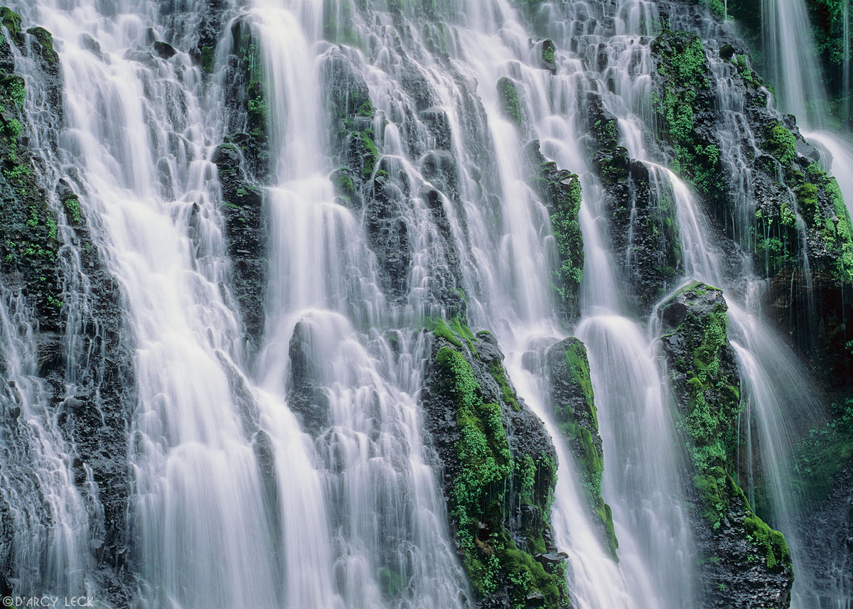 Water of Burney Falls streams down a verdant cliff at McArthur-Burney Falls Memorial Park, California