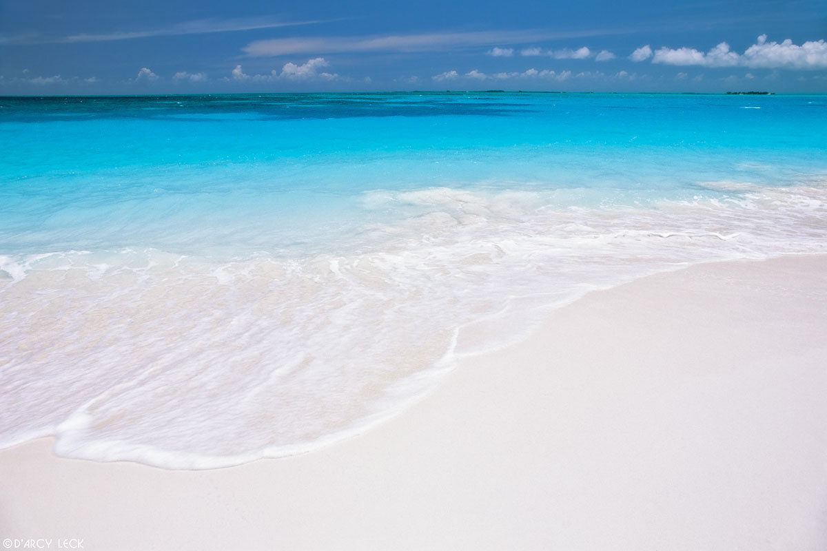 Surf laps a white sand beach with aquamarine waters beyond at Treasure Cay, Bahamas