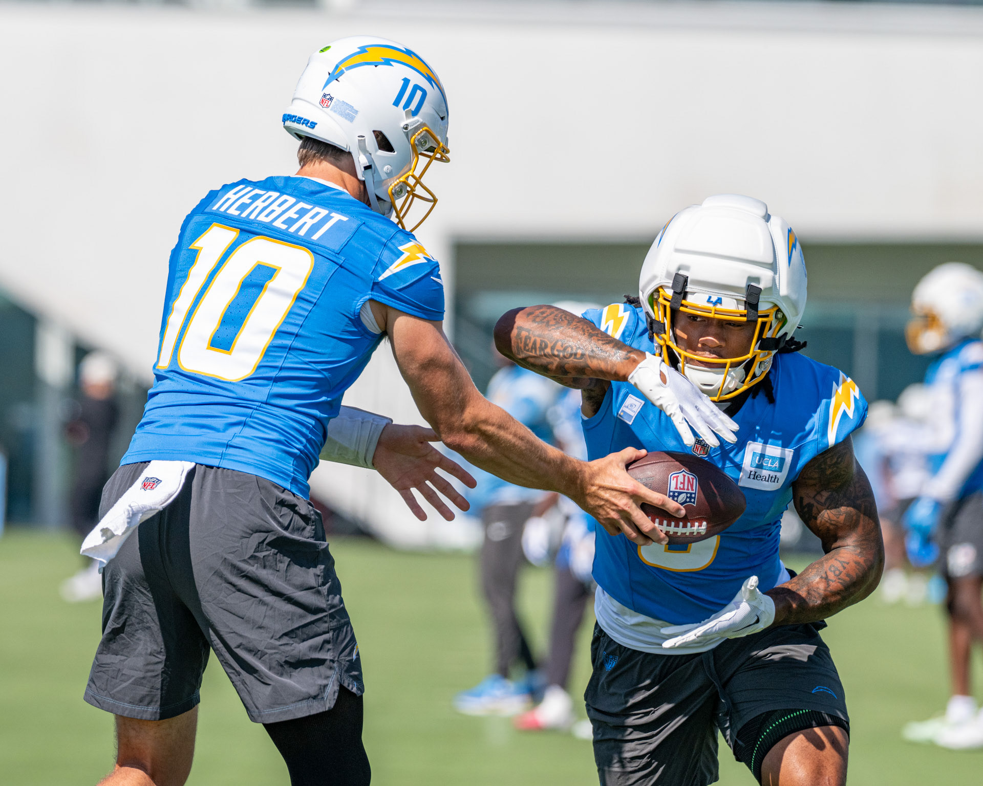 LA Chargers Justin Herbert (#10/QB) hands the ball off to Omarion Hampton (#8/RB) at 2026 summer training camp.
