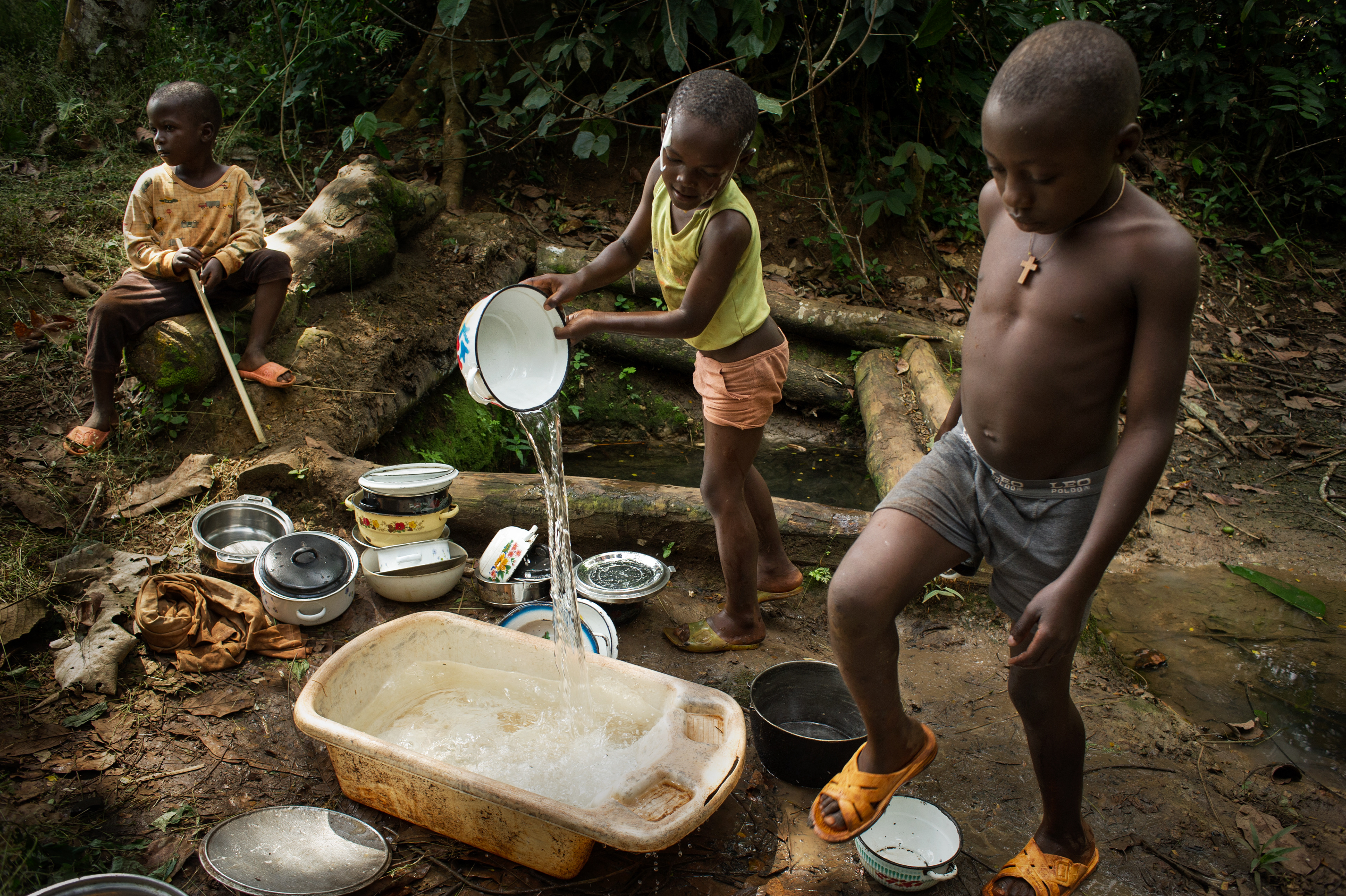 4 siblings wash dishes in a pond in the forest surrounding the town of Abong-Mbang. The house they live in has no access to water or electricity. Cameroon 2012
