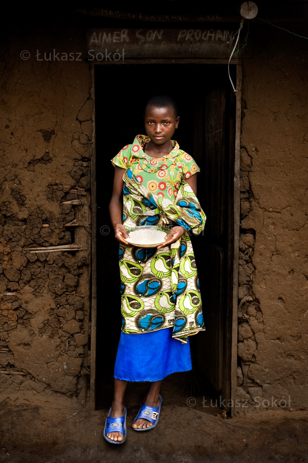 Alice Barabonerana, aged 14. She is an orphan, her father was killed during the war, he mother died during an operation. She lives in a house together with 4 siblings. Their family do not help them. After school she goes to the forest to bring brushwood (needed for cooking) and she does her homework. She gets the rice from the Sisters (food distribution program that covers particular families), it is the most valuable for her, because she can eat bellyful of it. She wants to be a nun to help other poor people. She dreams about her parents who help her. Rutshuru, DR Congo, 2010