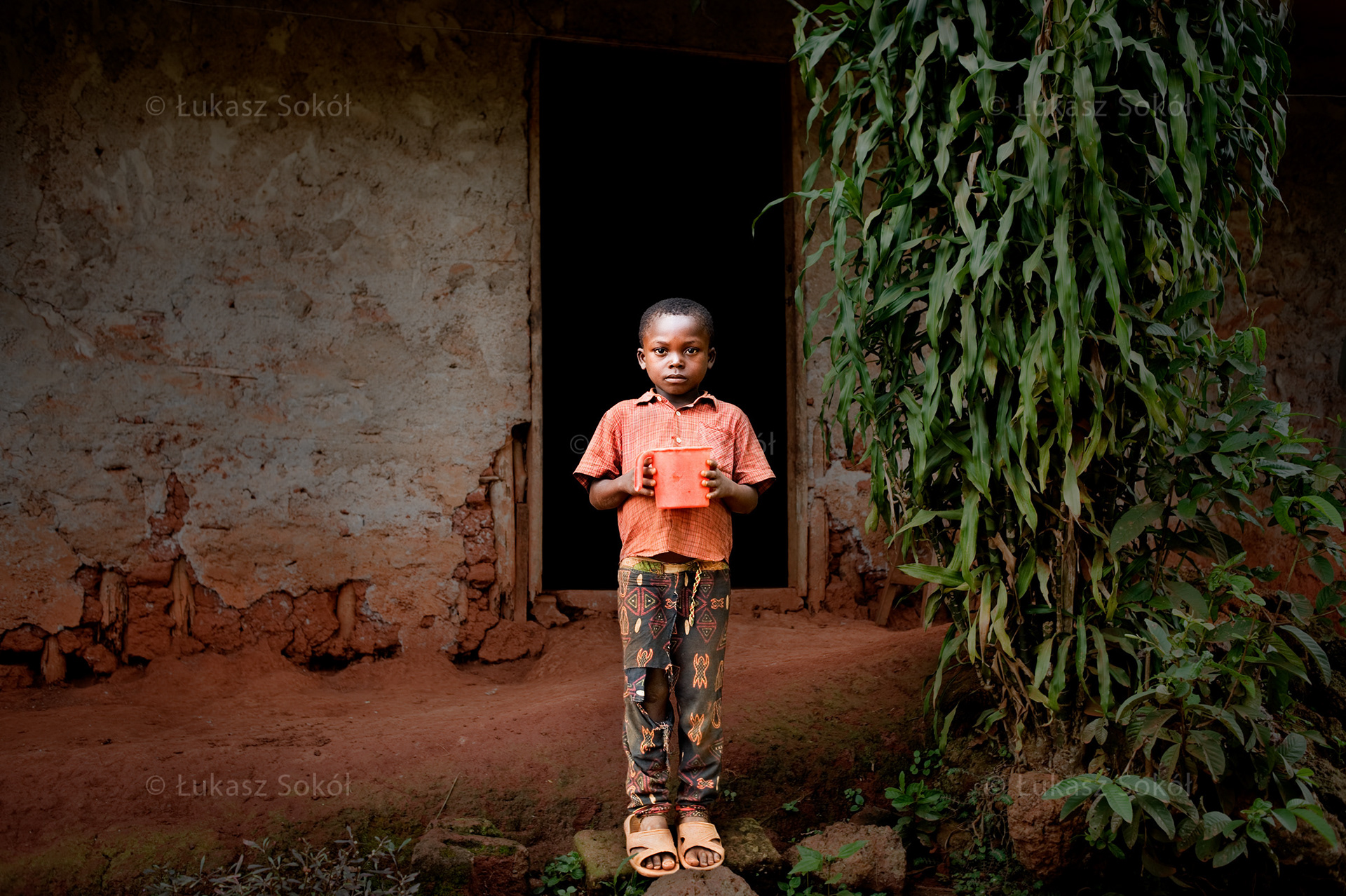 Saf Diani Vitrel, 6 years old, he has 3 sisters and 2 brothers. After school he washes the dishes. He is going to be a teacher. He drinks water and malaria medication from his orange mug. Ouama, Cameroon, 2009