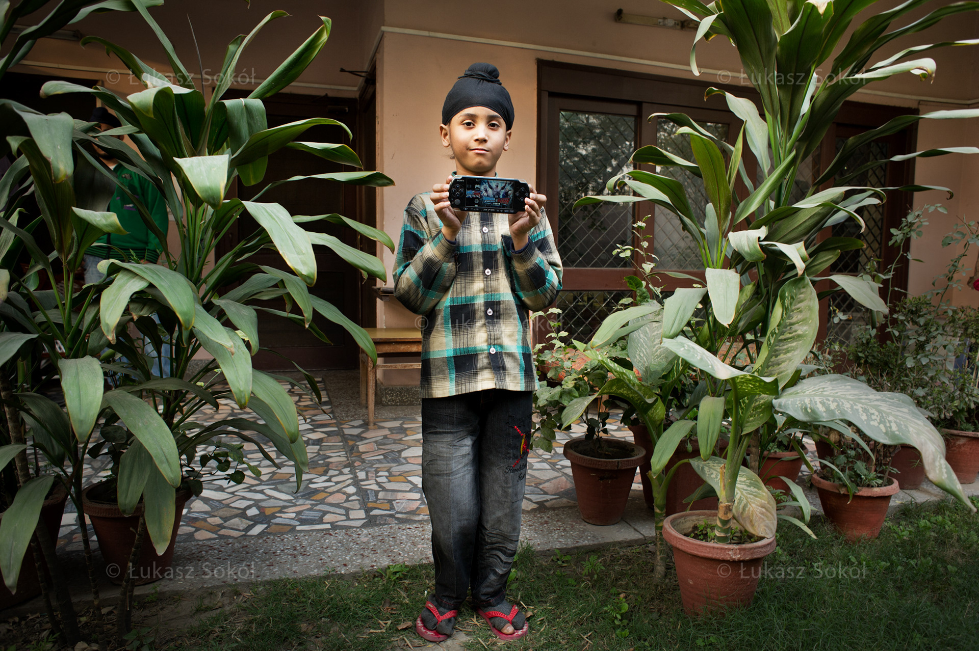 Karanjot Singh, 8 years old. He is the only child. The PSP console is a Christmas present from his uncle from America. He loves playing games on it, especially football. He must be at school at 6:30am so he gets up at 5am, though he doesn't like it. After lunch he goes to private lessons. He comes back home at 5:30pm, drinks a cup of milk and watches cartoons on TV. He wants to be a doctor.  New Delhi, India, 2012
