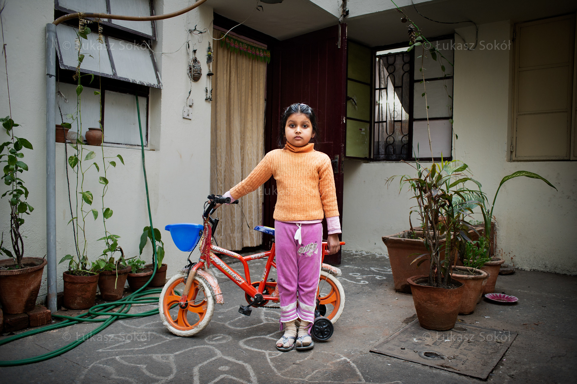 Kashish, 5 years old. She is the only child. She got the bike from her father. She loves riding it. She goes to the kindergarten. At home she does her homework with her mum, and later she rides a bike. When she grows up she wants to be a doctor.  New Delhi, India, 2012 