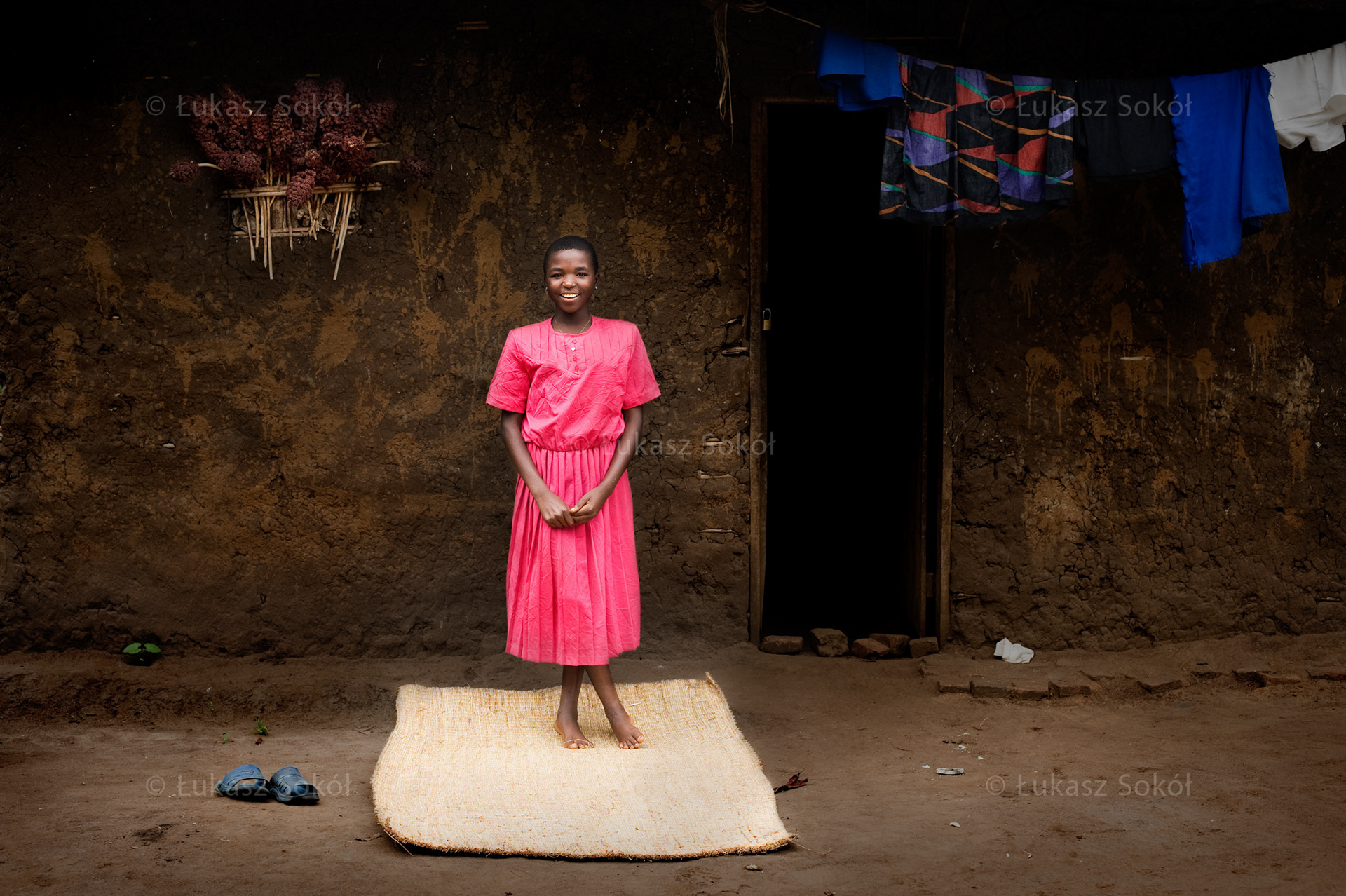 Renata Niranze, aged 14, a 4th grade student of primary school. Her father was killed in the field, probably during the war. She lives with her mother and 4 siblings. After school she fetches water. The mat was made for her by her mother. It is very important to her, because she sleeps on it. She dreams to have a real mattress. In the future she wants to be a nun to serve God. Rutshuru, DR Congo, 2010
