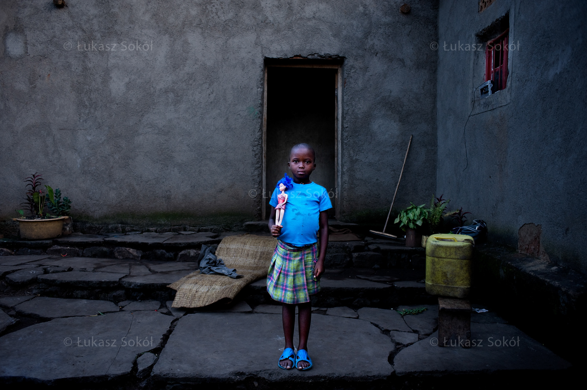 Marie Rosine Mukundente, aged 7, a 2nd grade student of primary school. She lives with her parents and 10 siblings (2 adopted ones). She fetches water 4 times a day (a 5-litre container), she looks after younger brothers and sisters as well as the neighbours’ children. She got the doll as a present. She often carries it on her back copying other adult women with children. The doll is white, that is why she likes it so much. When she grows up, she wants to be a nun or a doctor. Nyakinama, Rwanda, 2010