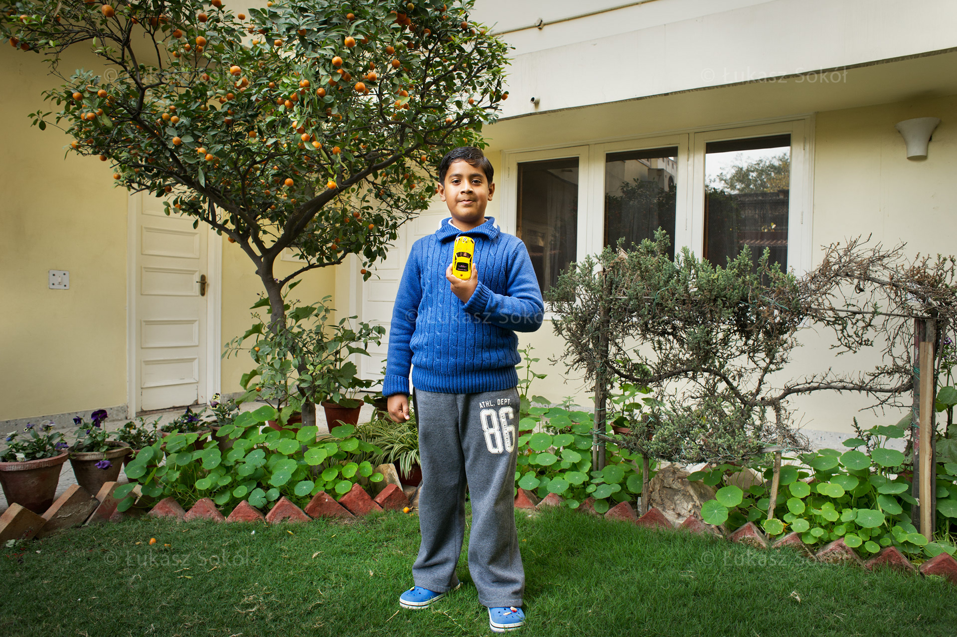 Aditya is 8 years old. He has 5 sisters. He brought the sports-mercedes-shaped mobile phone from Bangkok, where he was with his parents. He likes it because it is new and original, has 2 games and a lot of telephone numbers and information. Most often he calls his parents, grandparents, sisters and his drivers. When he grows up he wants to be a doctor and help people. He goes to school from 7:30am to 1:30pm. When he comes back home he eats dinner and watches TV. Then he goes out and plays cricket or football. In the evening he eats supper with his parents. At the weekends he goes to Gurgaon (a modern city close to New Delhi) with his parents to ride a roller coaster and enjoy other attractions. New Delhi, India, 2012