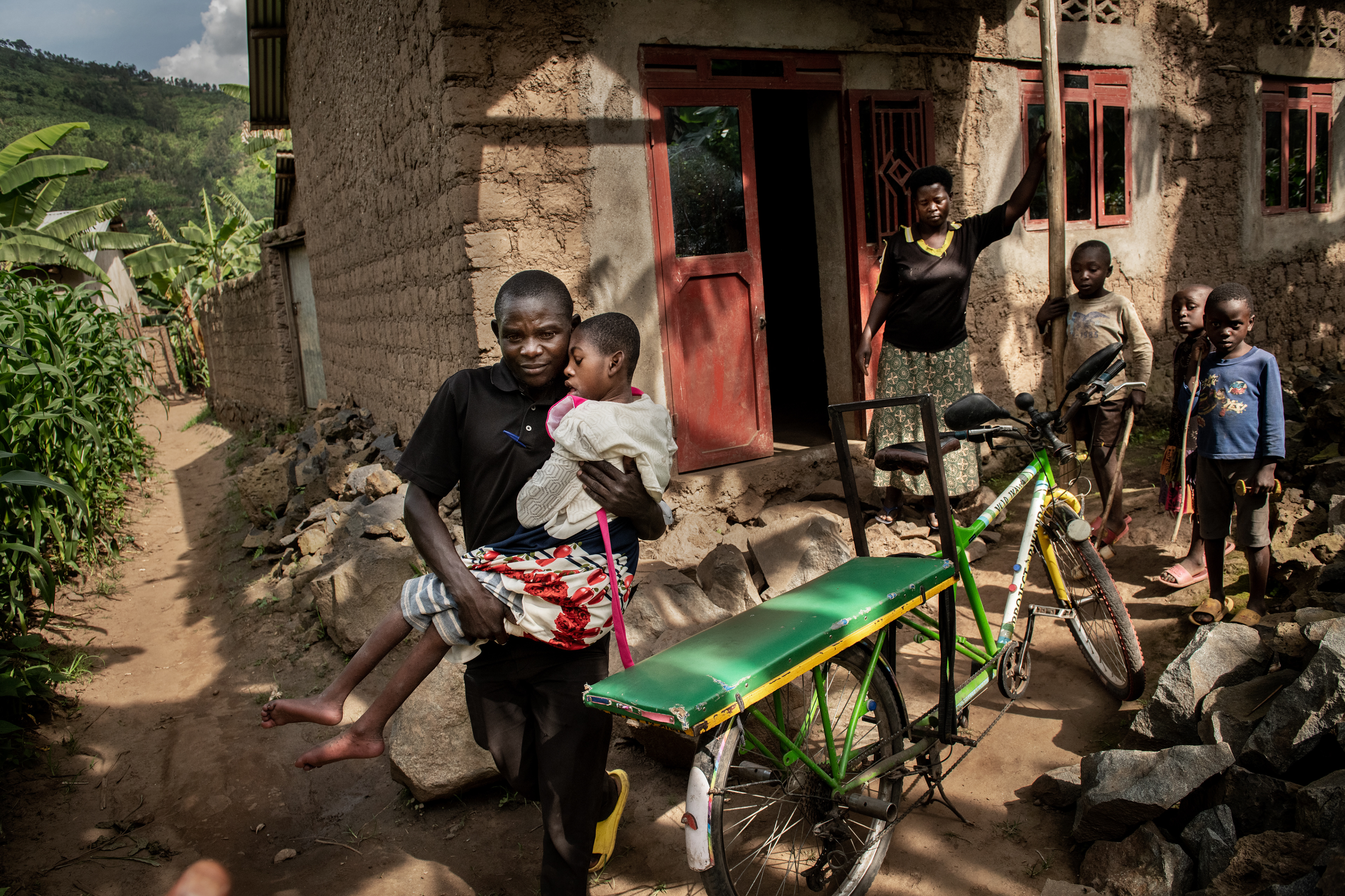 Claire (9 years old) Carried by her father, a bicycle taxi driver. She has epilepsy and mental disability. She spends her day sitting in a special chair or is being carried on her mother's back. Nyagahongo, Rwanda, 2022
