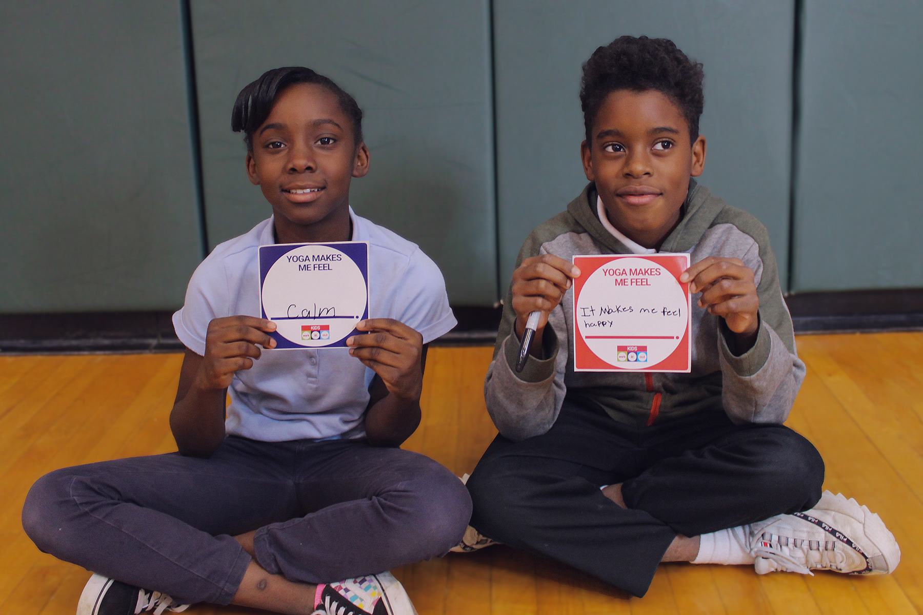 Students holding up their take-home "Yoga Makes Me Feel" cards.