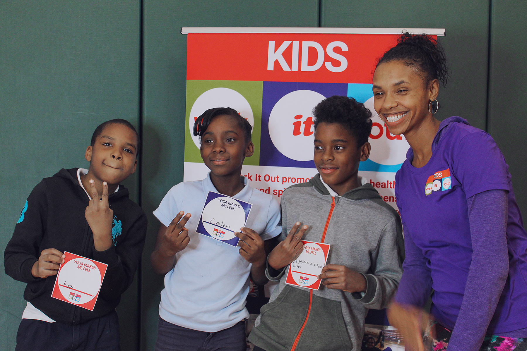 Students holding their "Yoga Makes Me Feel" cards with our Yoga Instructor, Adrienne.