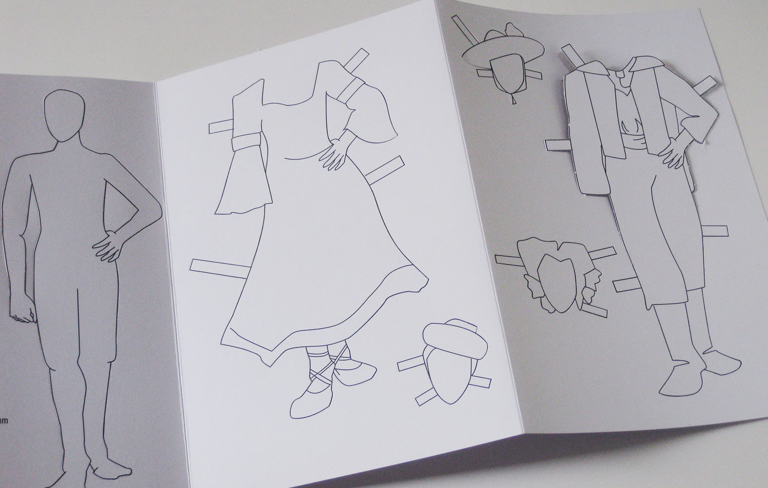 The inside of an open brochure, with illustrations of a paper doll including a body, two Spanish-inspired outfits and three head options to punch out.
