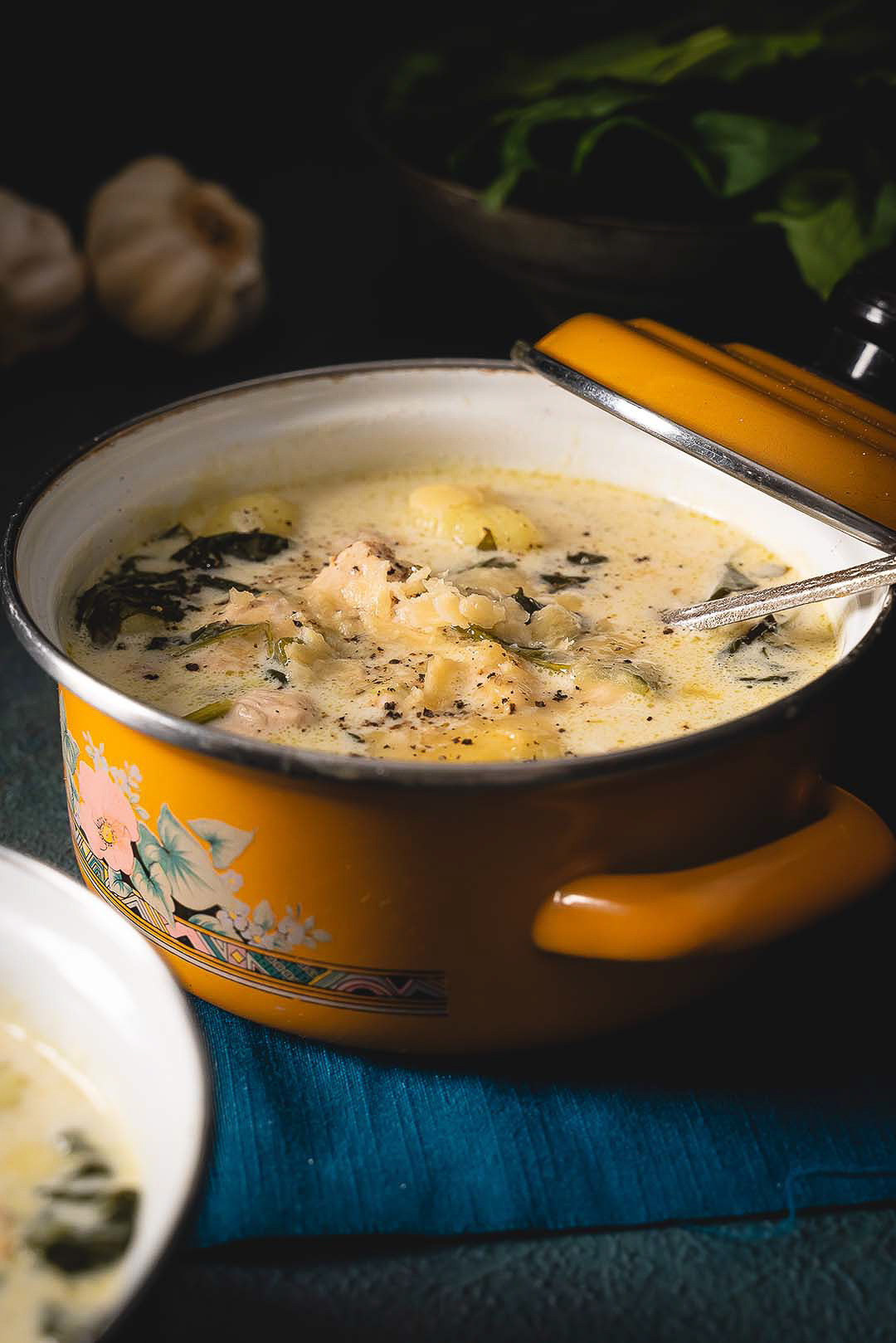 Creamy Gnocchi Soup: Spinach & Parmesan Elegance - Set against a dark backdrop, this striking image features a yellow enameled pot filled with a rich, creamy gnocchi soup infused with fresh spinach and a sprinkle of Parmesan. The captivating blend of traditional flavors and modern presentation makes it a visual treat for food enthusiasts.
