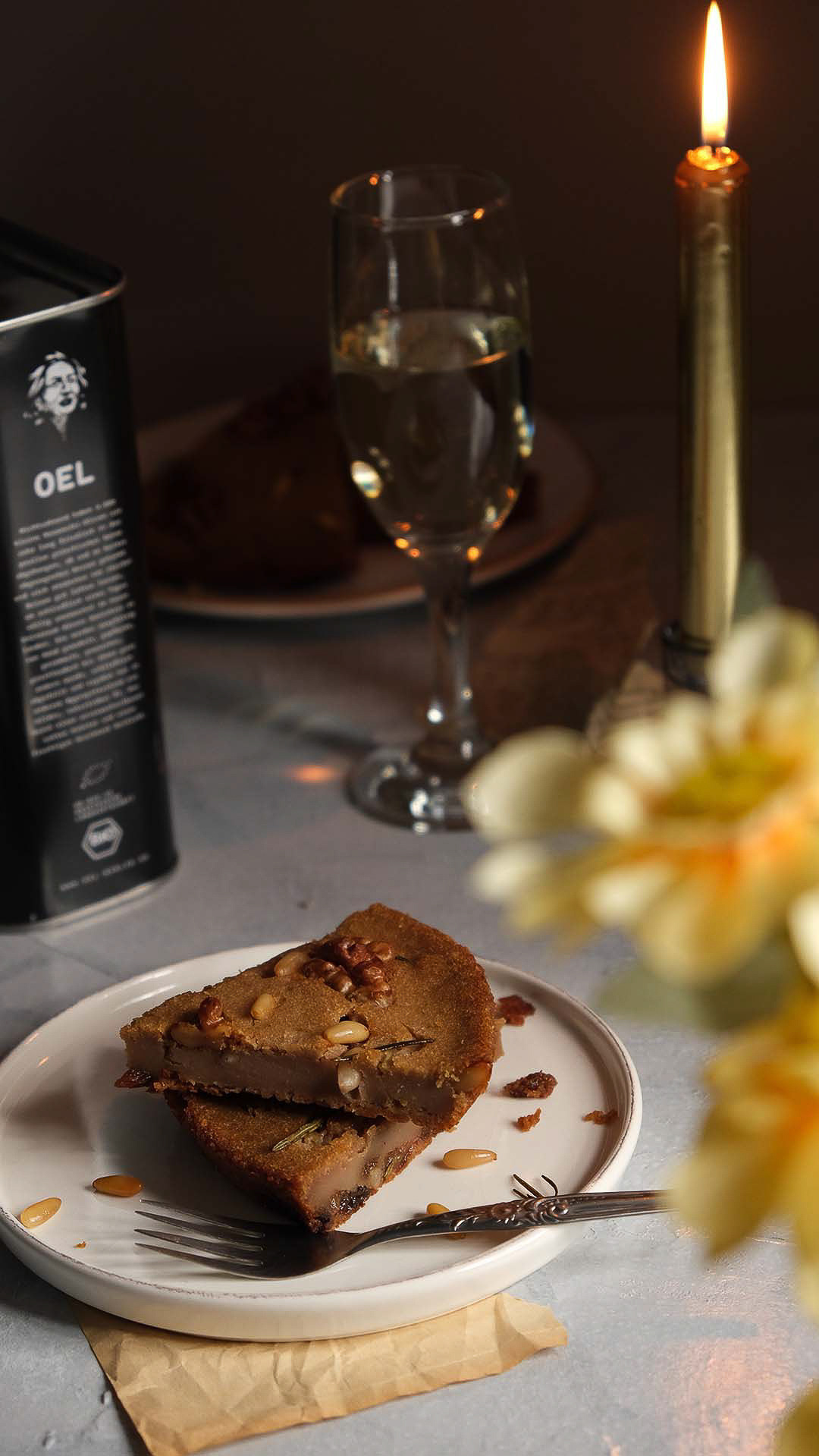 Castagnaccio & Processo: Dark Still Life for Oel Berlin - Shot for Oel Berlin, this evocative still life pairs a traditional castagnaccio dessert with a glass of Processo. Illuminated by the warm glow of candlelight, the composition exudes modern sophistication while honoring culinary tradition.