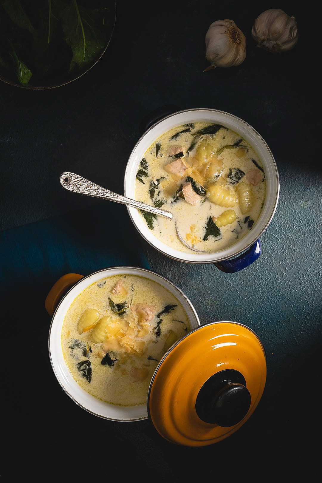 Creamy Gnocchi Soup: Spinach & Parmesan Elegance - Set against a dark backdrop, this striking image features a yellow enameled pot filled with a rich, creamy gnocchi soup infused with fresh spinach and a sprinkle of Parmesan. The captivating blend of traditional flavors and modern presentation makes it a visual treat for food enthusiasts.