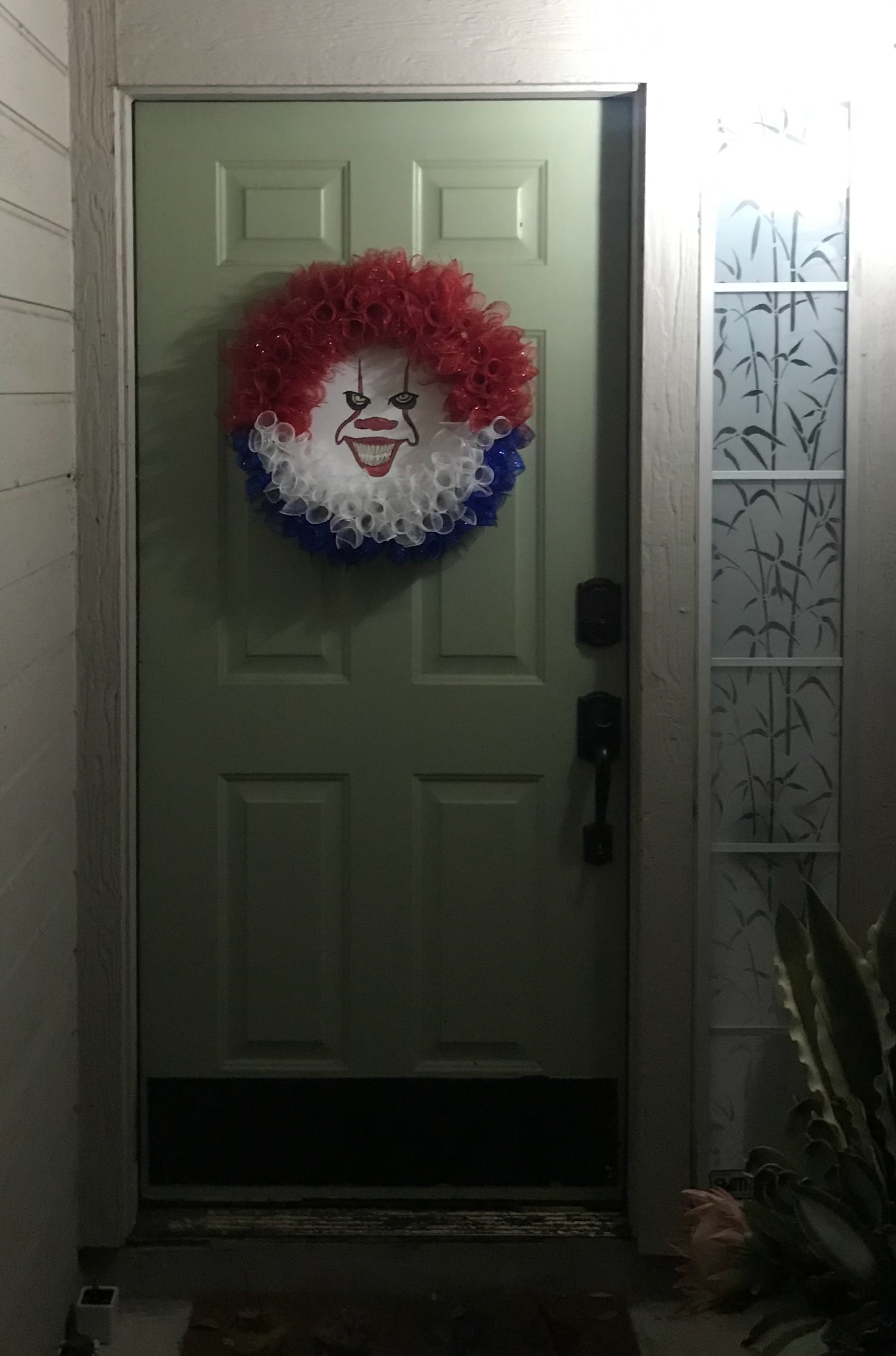 Door wreath of Pennywise from "It"; painted on flat canvas, collaboration with wreathmaker.