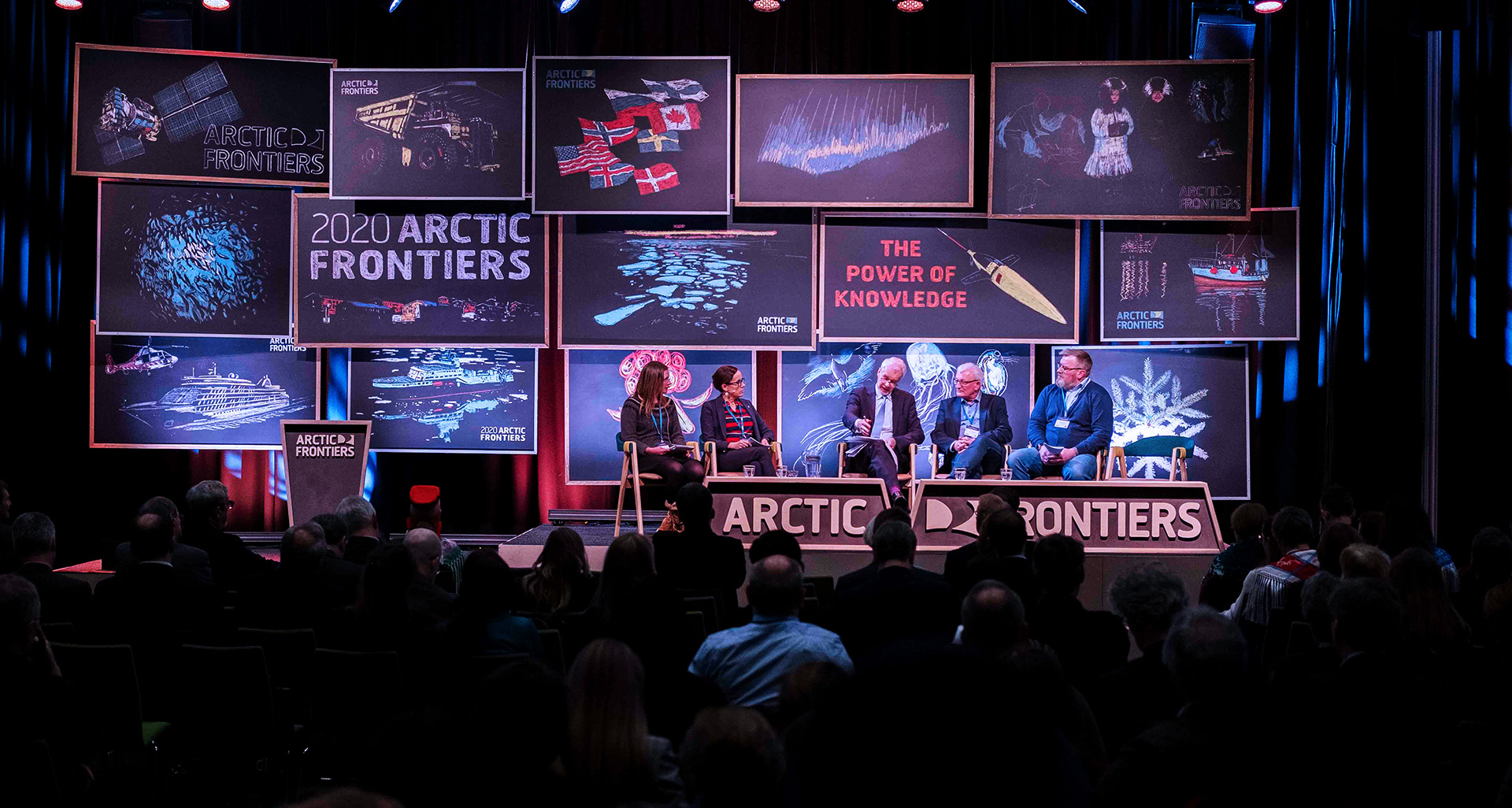 Photo of stage with panel and audience.