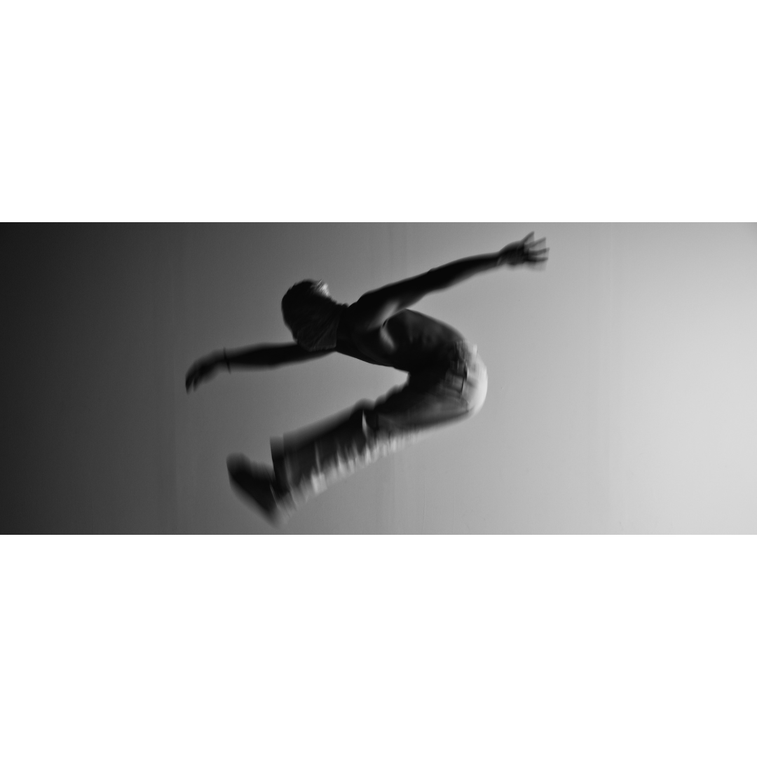 Image of masked model wearing white jeans performing a static jump with arms in the air