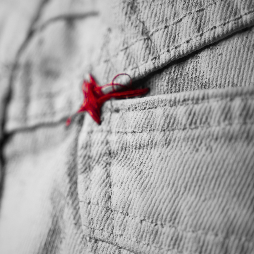 Macro black and white photograph of white Bianchetto denim pocket with red cross detail, selective colour, Margiela fashion photography, MINUSELEVEN AUDIOVISUAL