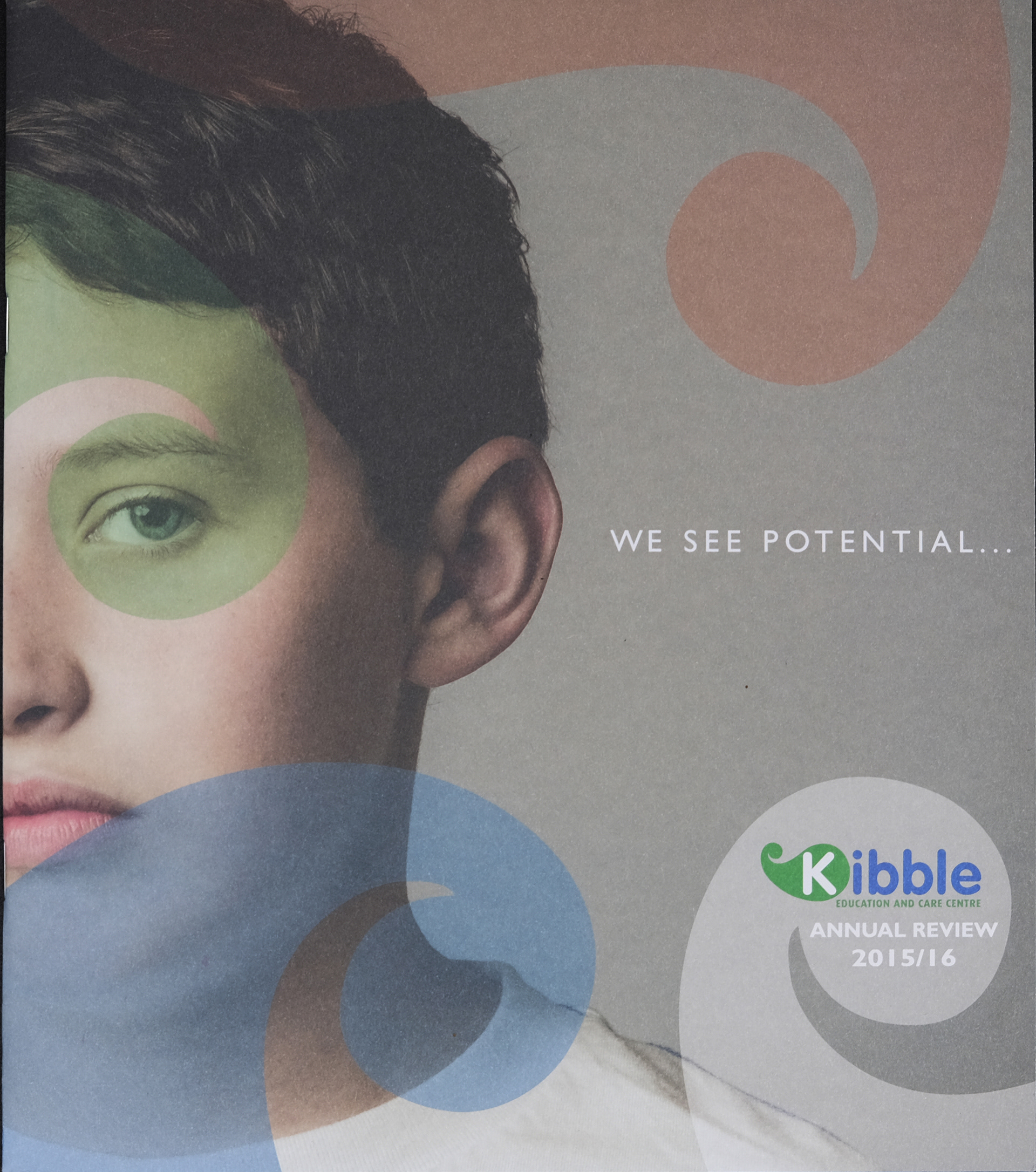 Front cover of Kibble annual review showing half of a boys face with kibble logo in transparent blue green and red