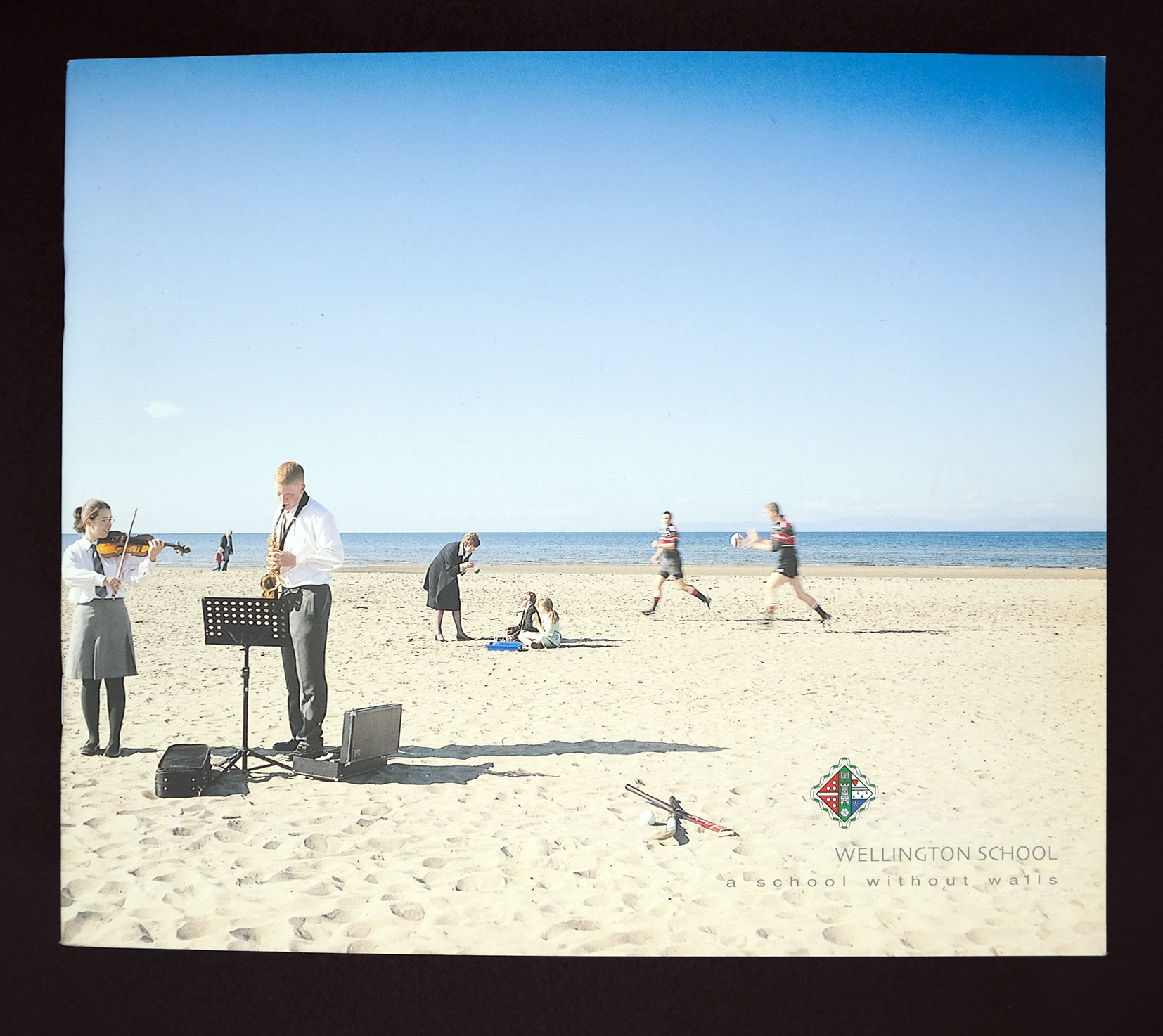 Wellington School brochure showing school children on the beach playing instruments, being taught chemistry, and playing rugby 