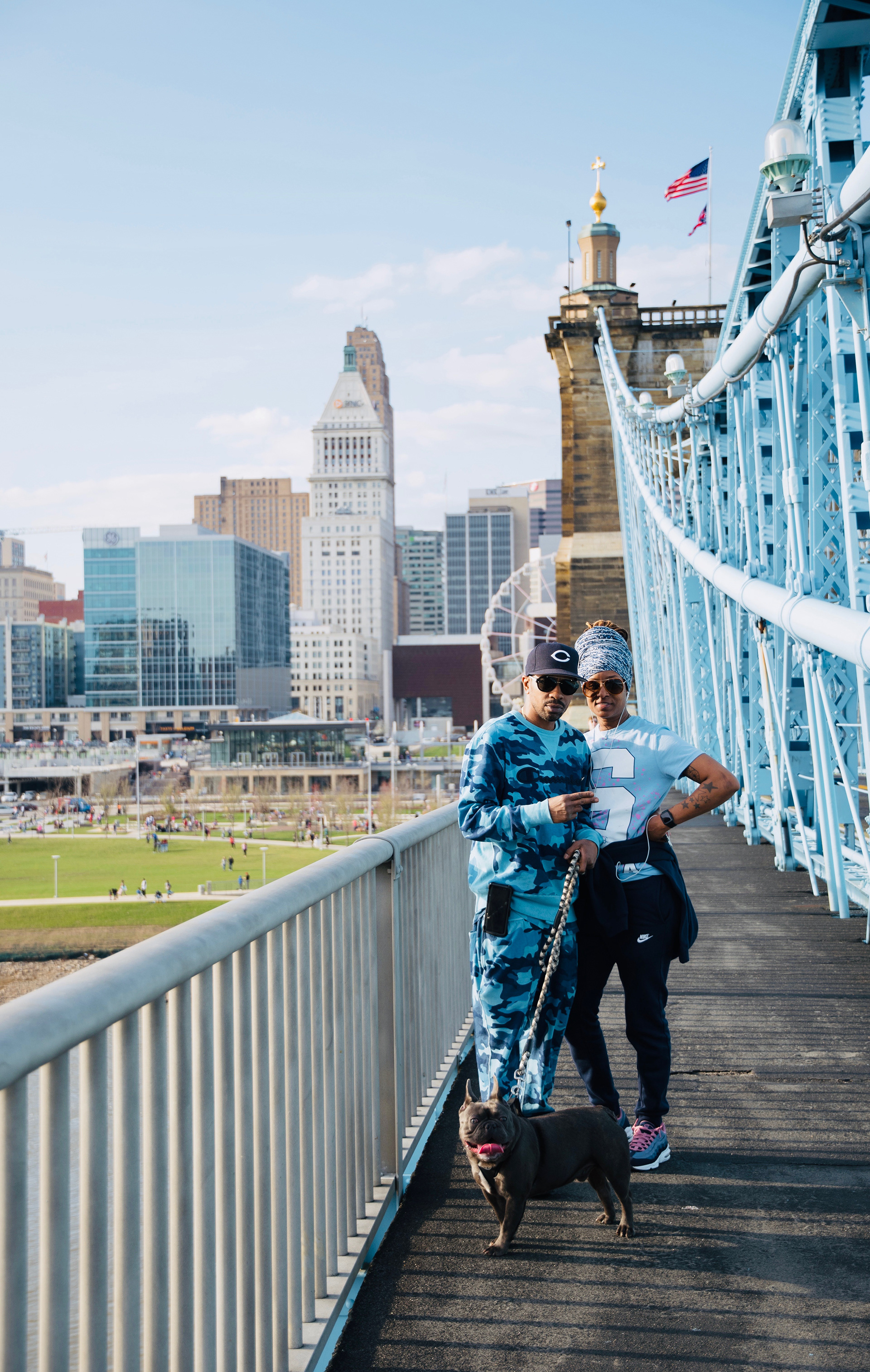 A couple poses with their French Bulldog on Roebling Bridge in Cincinnati