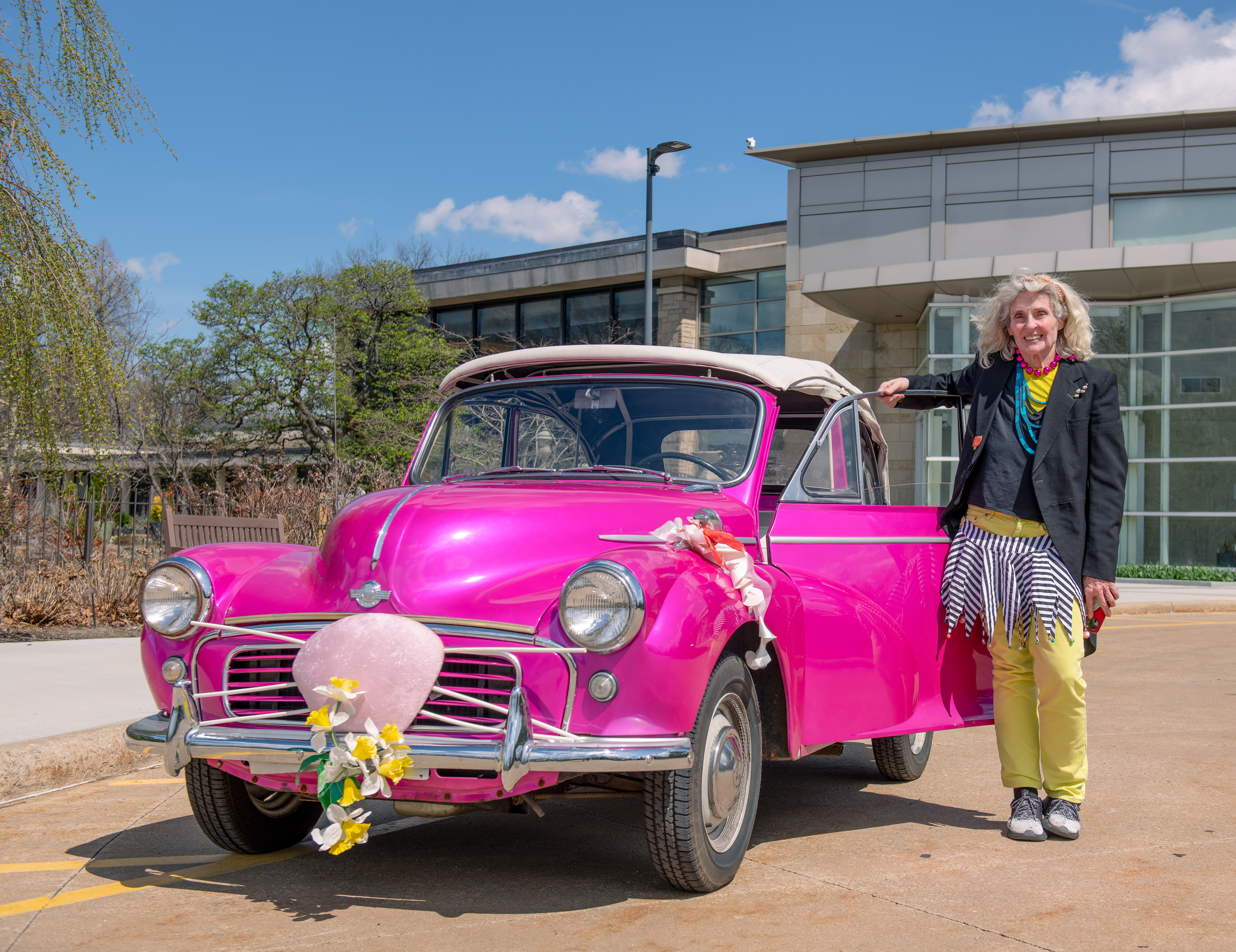 A proud car owner poses with her vehicle, dressed up as the Easter bunny