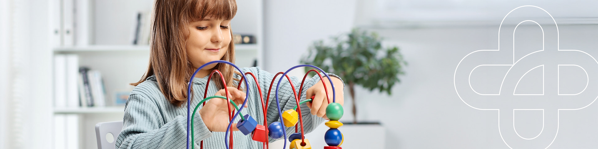 Lächelndes Mädchen beim Ergotherapie-Spieltraining mit Motorikschleife in freundlicher Praxisumgebung.