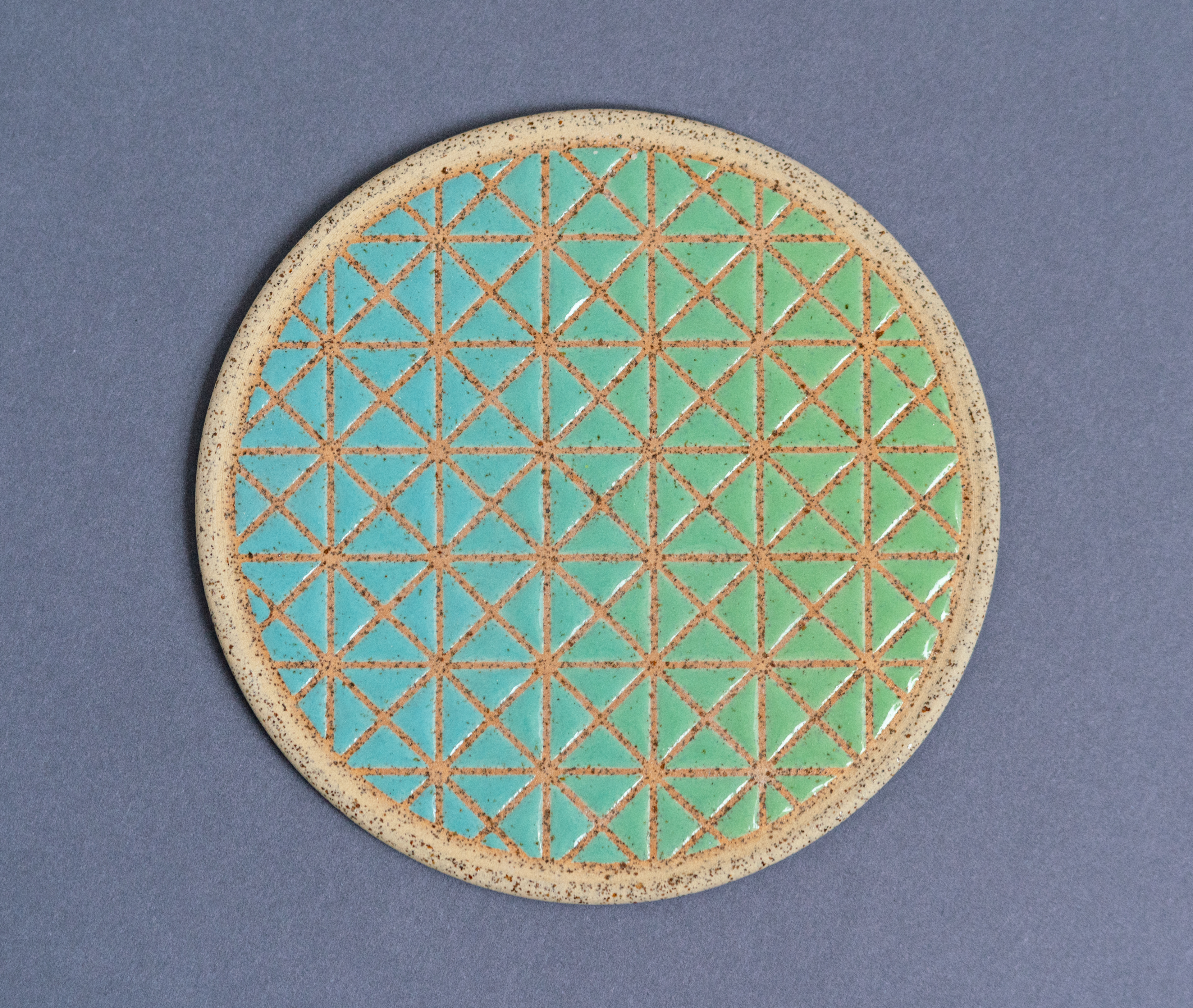 Stoneware wall tile with a pattern designed digitally and glazed using mason stains mixed with clear glaze to create a gradient
