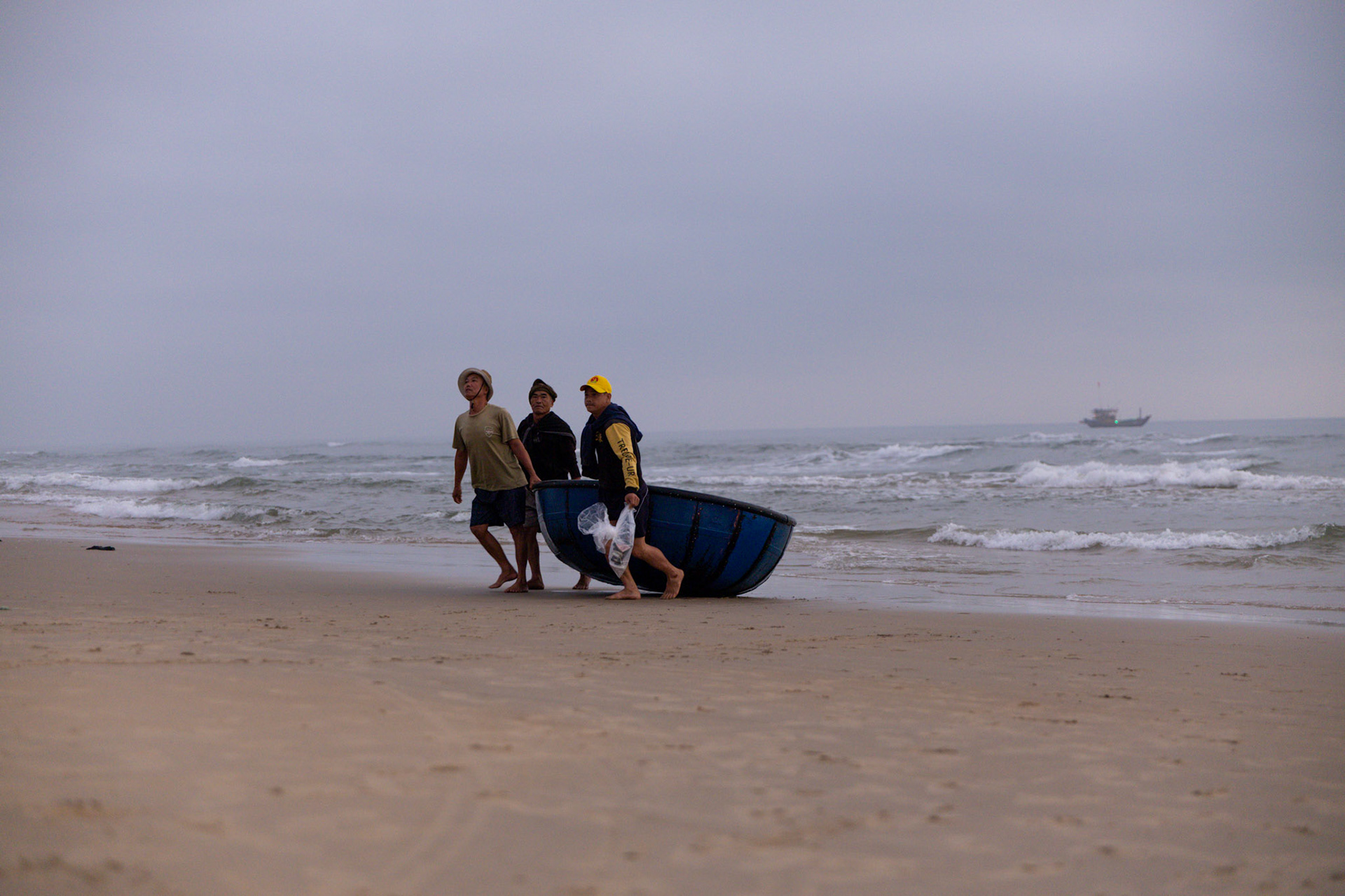 A quiet rhythm unfolds as fishermen bring in the day's work, where the ocean meets the shore