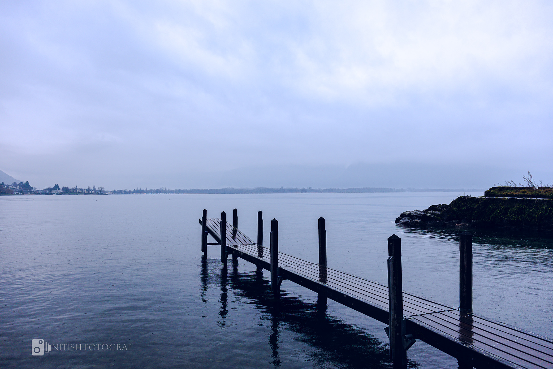A serene lake meeting the soft embrace of rolling hills