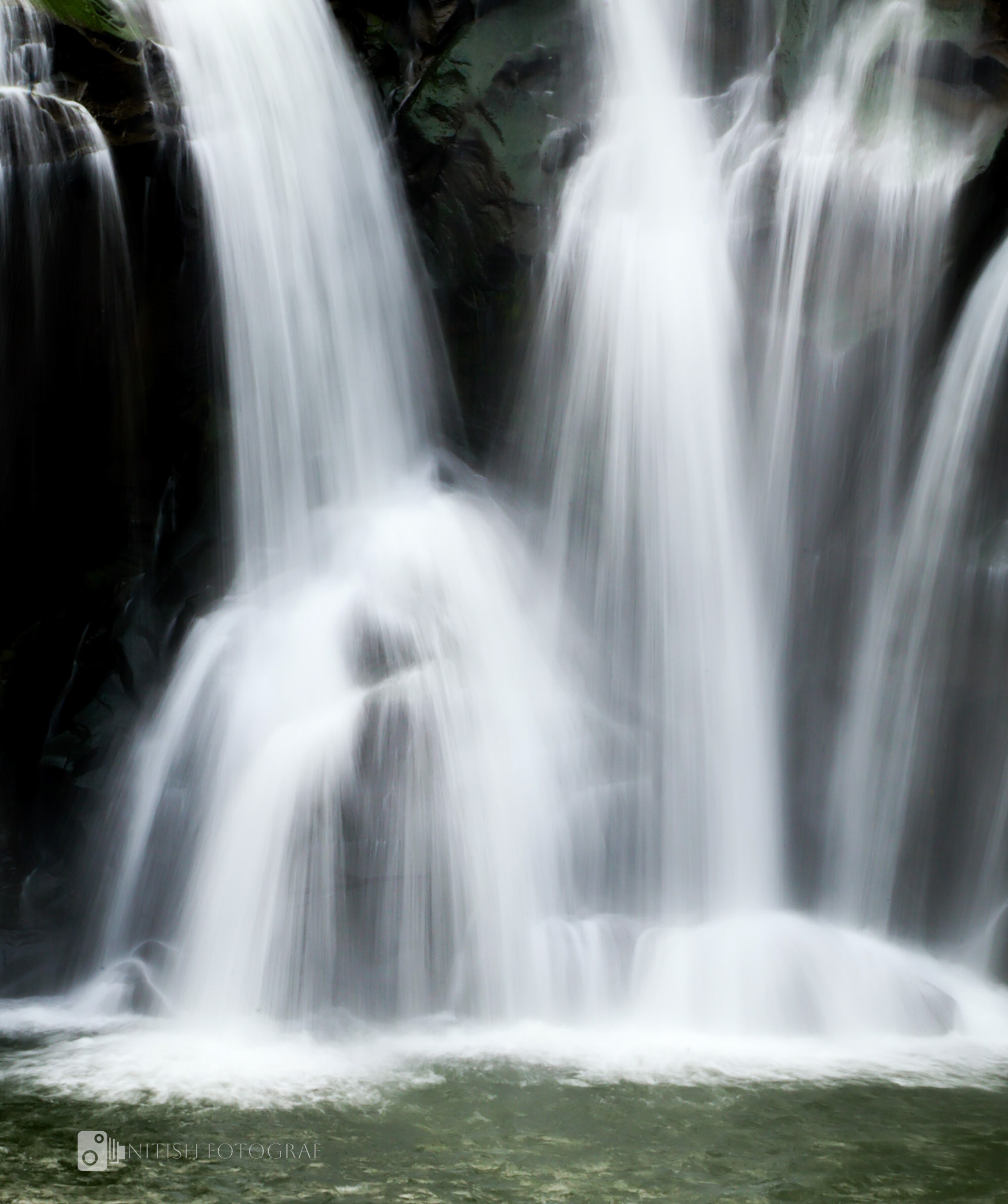 A delicate waterfall cascading like a sheer veil, amidst tranquil surroundings.