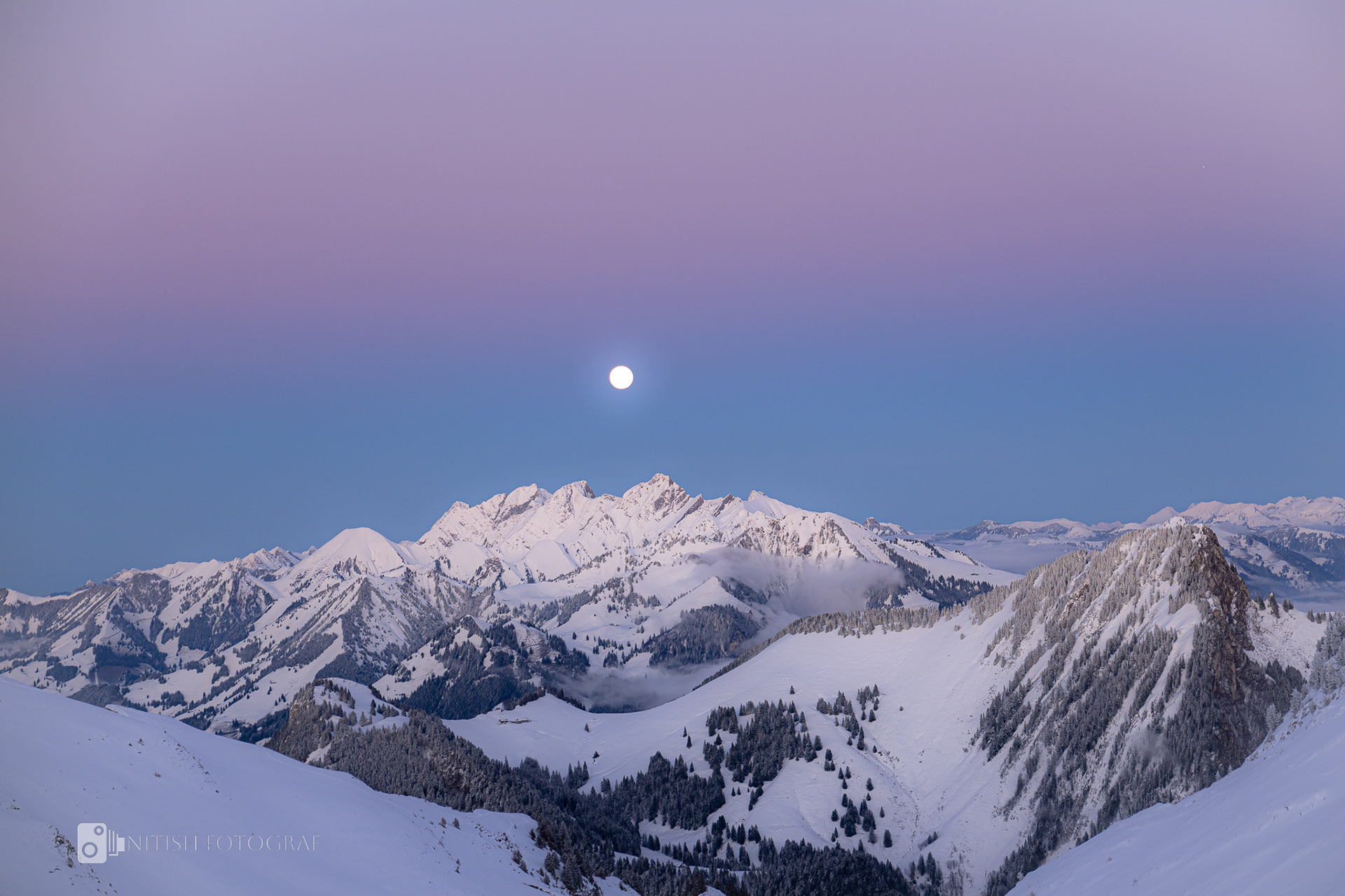 Snowy peaks glowing under the gentle hues of a fading sky