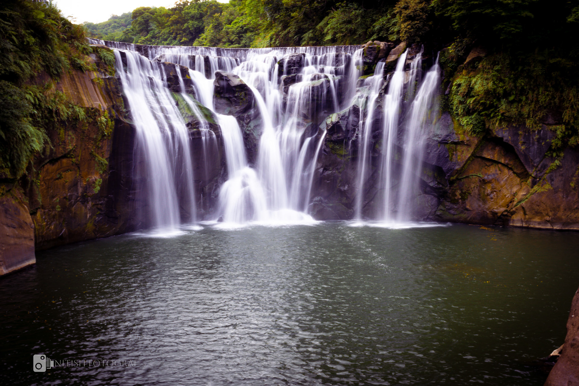 A waterfall flowing gracefully through lush greenery—a portrait of nature’s rhythm.
