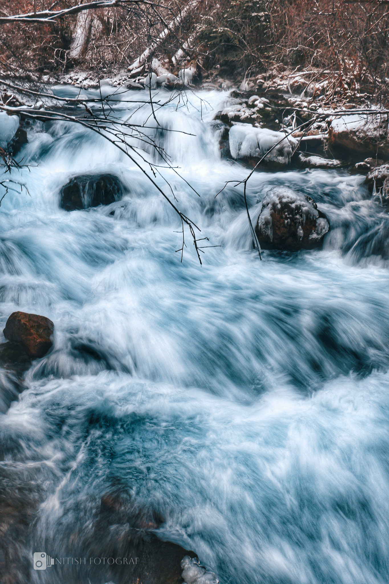 A cascading stream weaving its way through a rugged, timeless landscape
