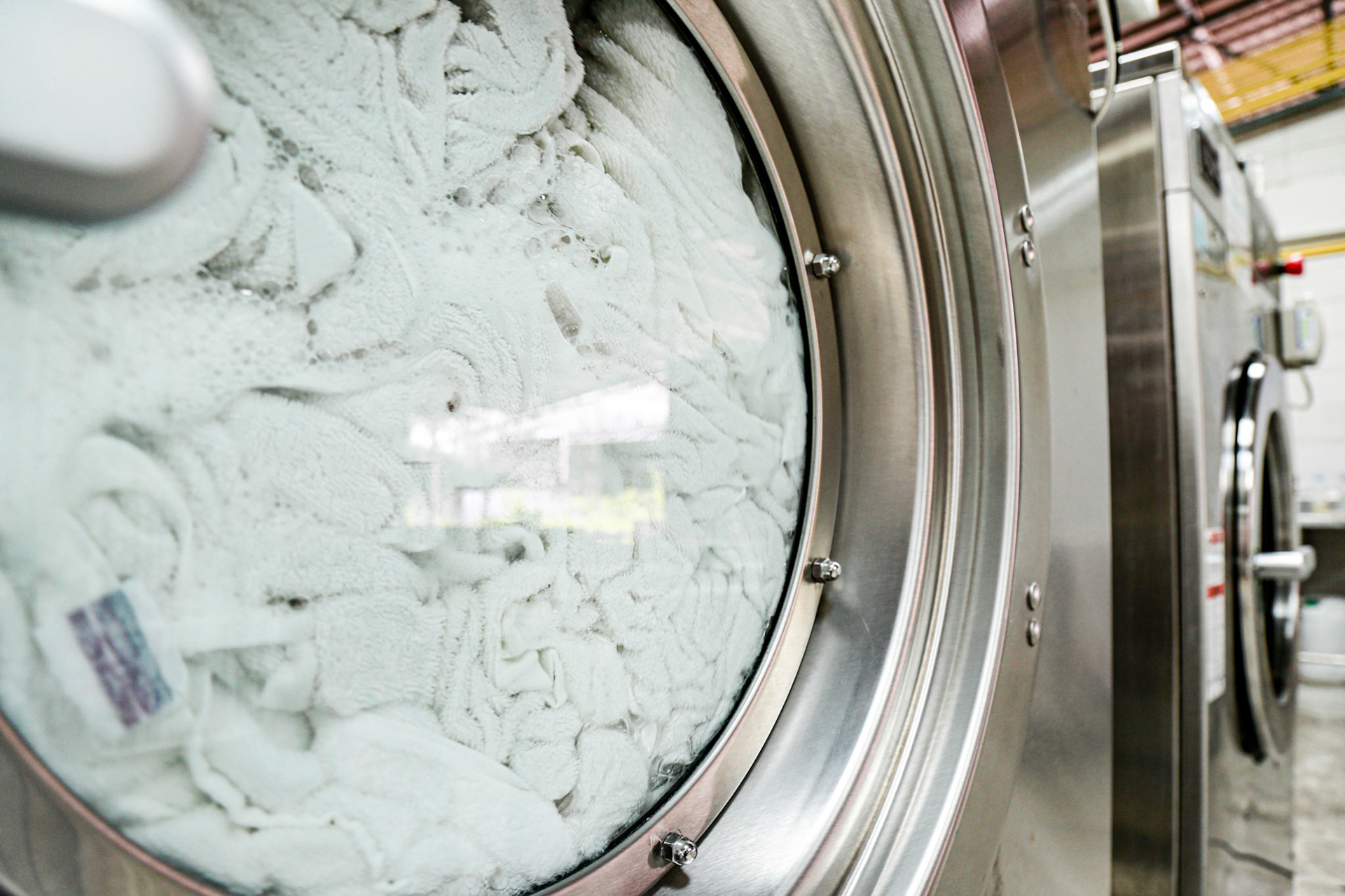 Towels are spinning inside a big front door of industrial washing machine. Shot taken in the factory.