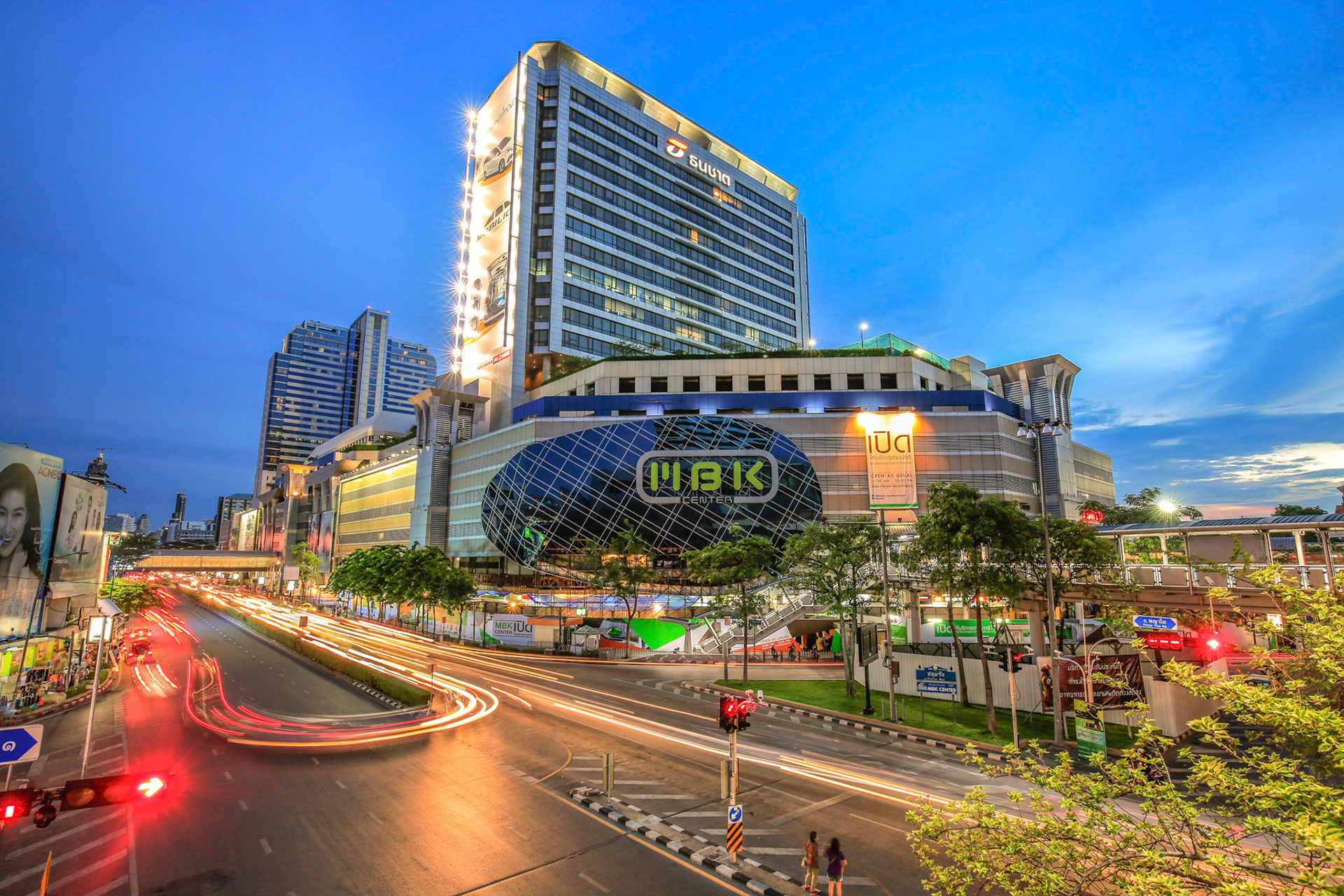 BANGKOK, THAILAND. Twilight cityscape of MBK shopping mall with traffic crossroads and car light trails. This photo was taken in the evening.