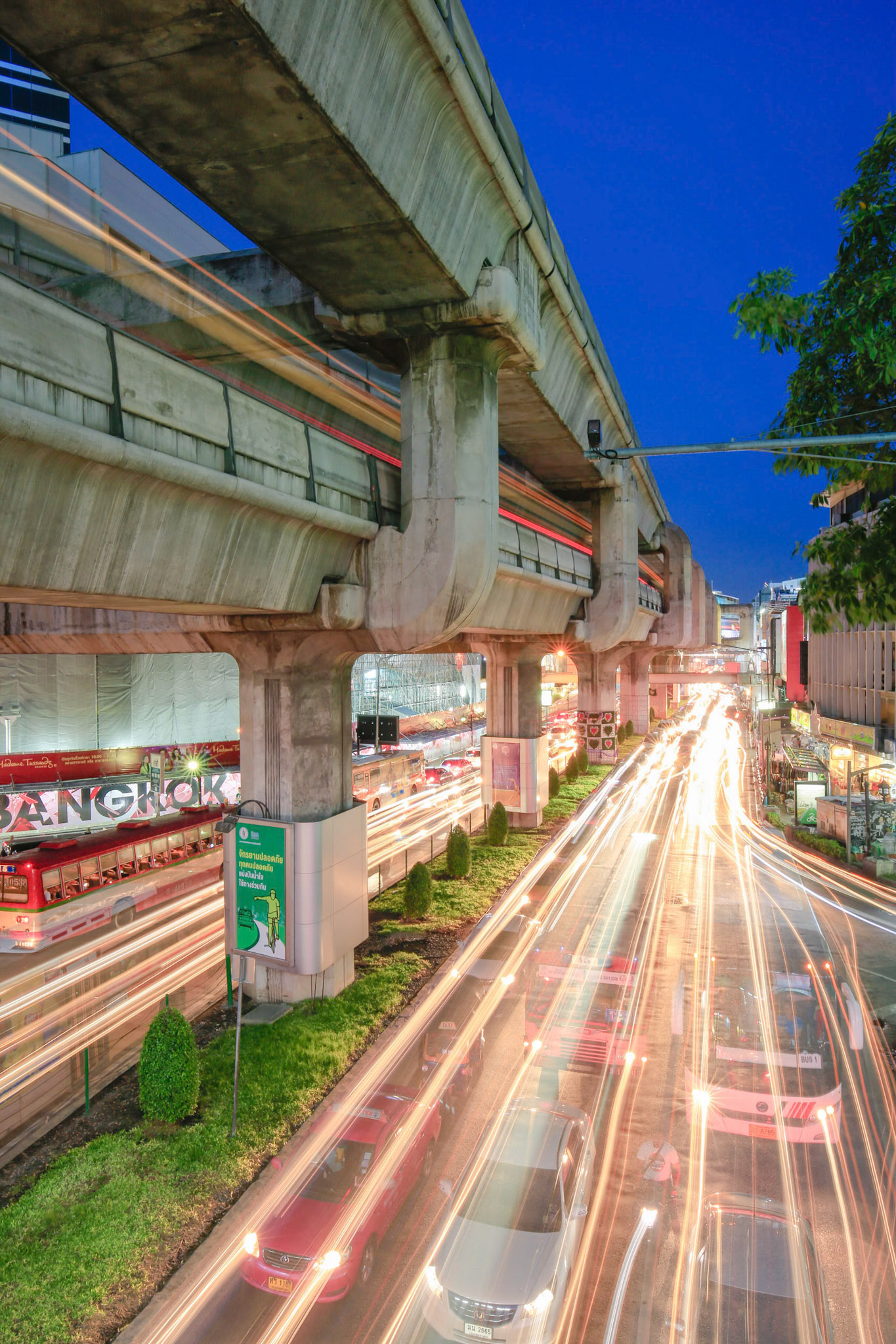 BANGKOK THAILAND - Twilight Bangkok with moving skytrain above car traffic and street lights.