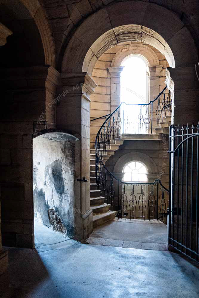Arch doorway. Light entering building through windows. Shadows and stairs.