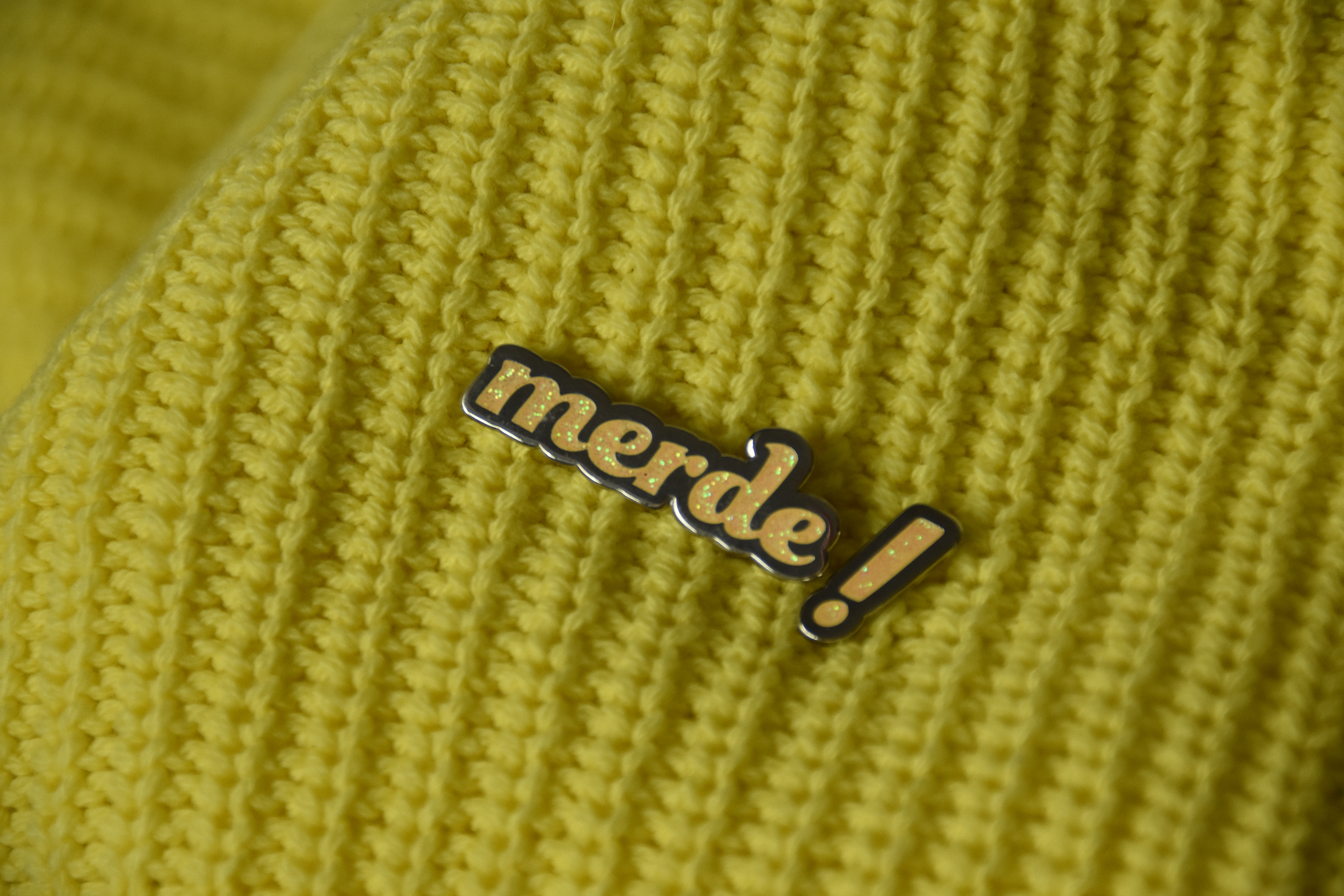 The "Merde" pin styled with the matcing exclamation point.